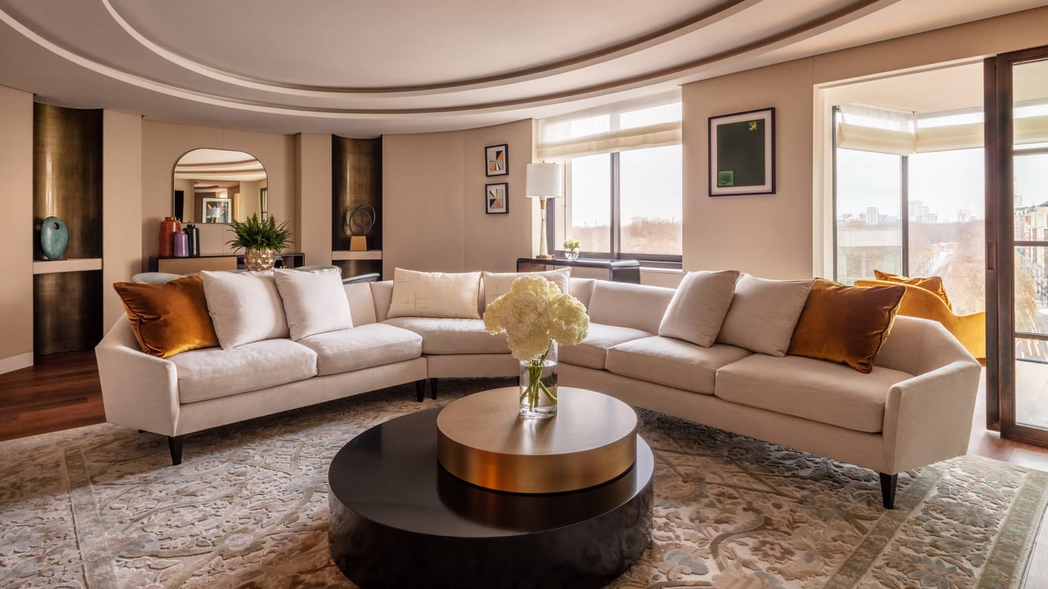 Hyde Park Suite living room with beige sectional, round coffee table with white flowers in vase
