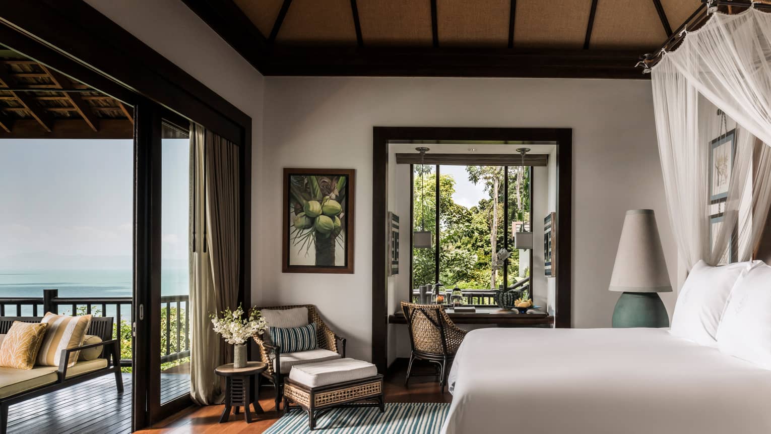 Deluxe One-Bedroom Pool Villa bedroom with bed, wicker armchair, open-air wall to patio