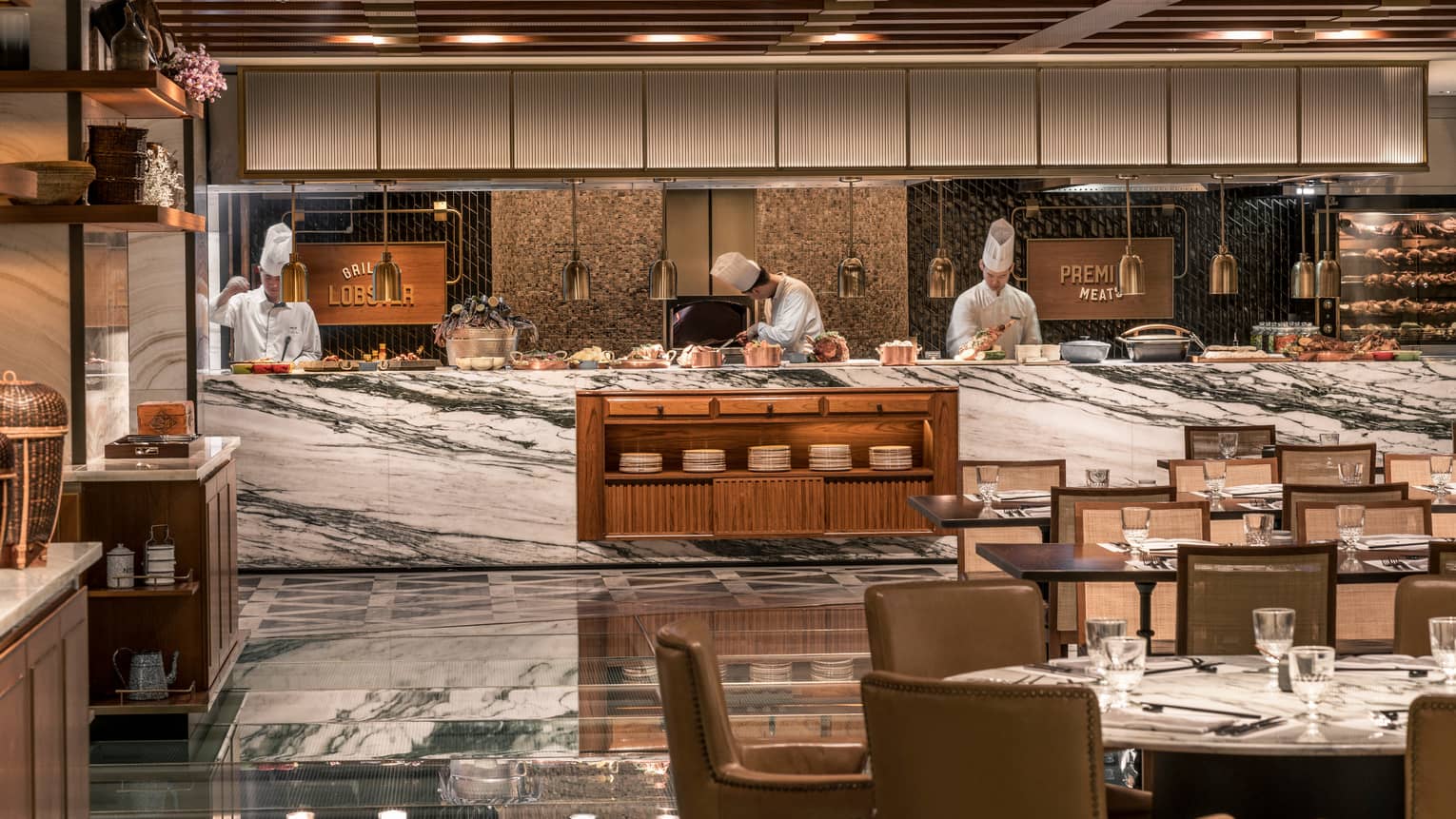 Chefs work behind white marble counter with copper pots at The Market Kitchen