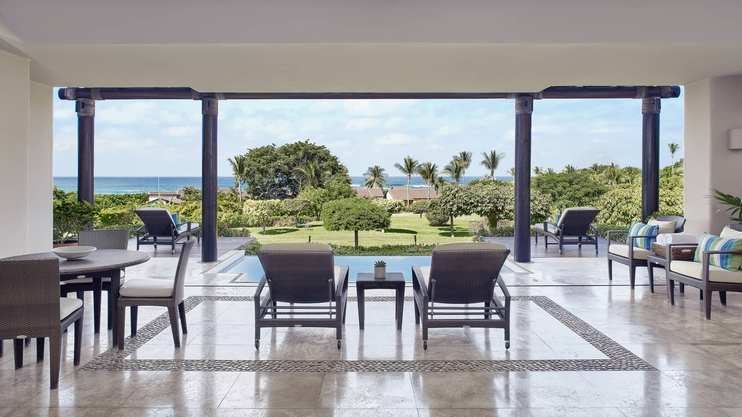 Terrace with dining table and lounge chairs, looking out to private pool and ocean in the distance