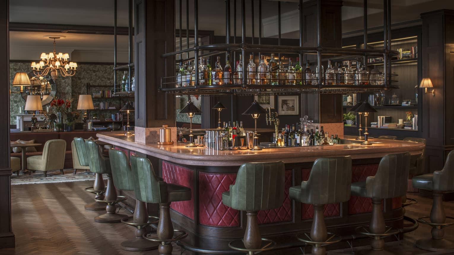 The Bar at Wild Carrot with red-wrapped and wood-accented bar, green barstools, and suspended spirits