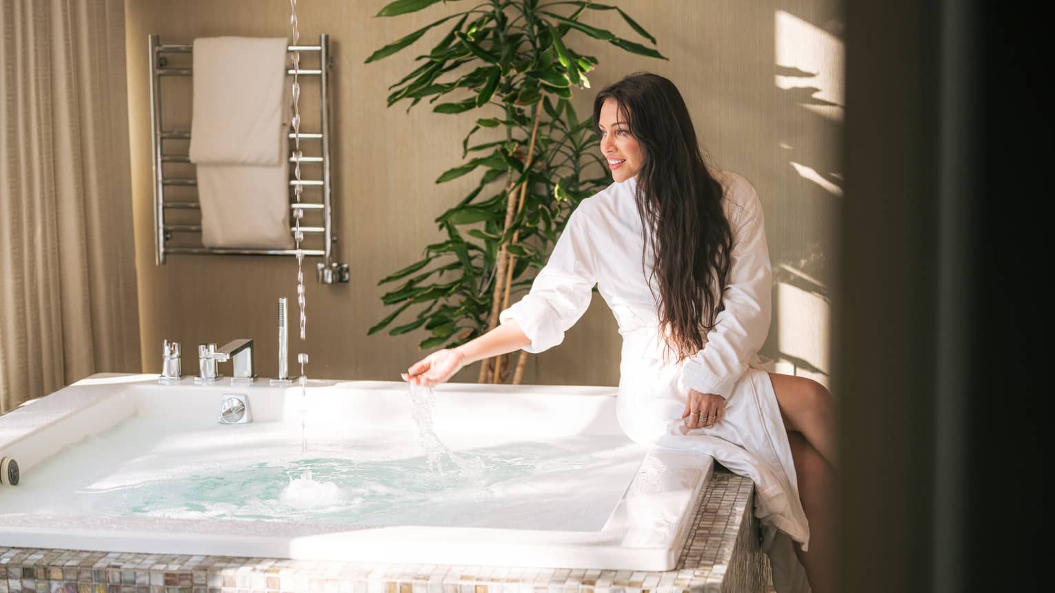 Woman sits at side of spa hot tub with spa robe on