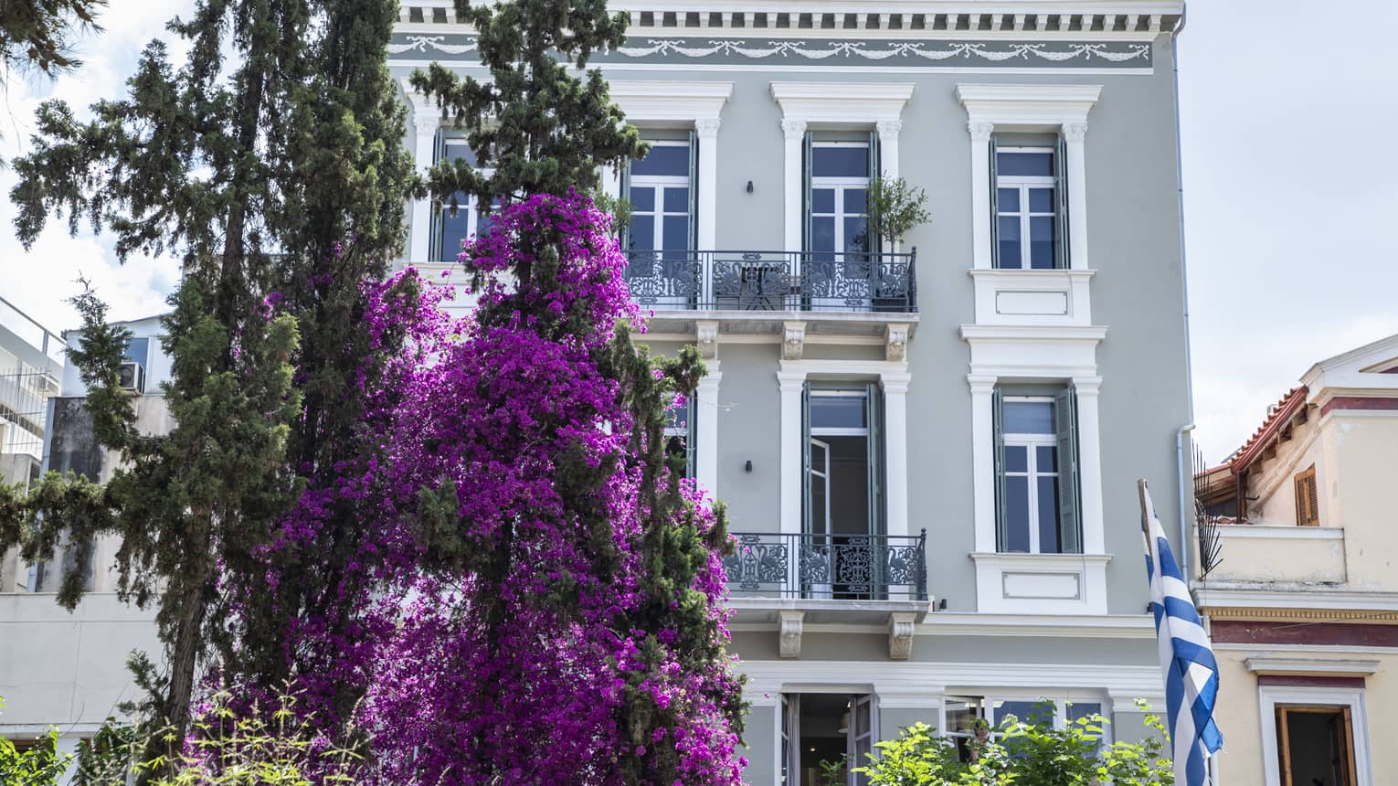 Exterior of a house in downtown Athens, Greece, with purple tree and Greek flag out front