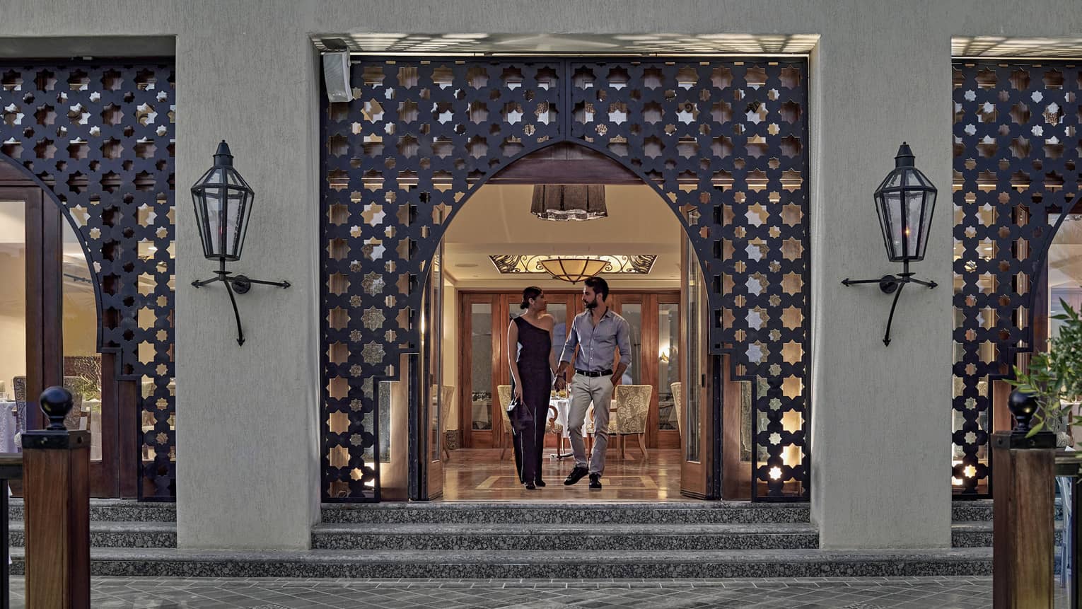 Man and woman walking out of a restaurant with Arabesque detailing around doorway