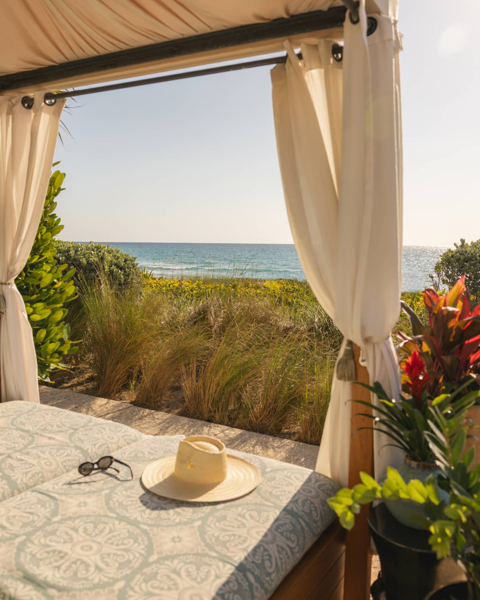 Beachside cabana overlooking the ocean with a hat lying on the cushion