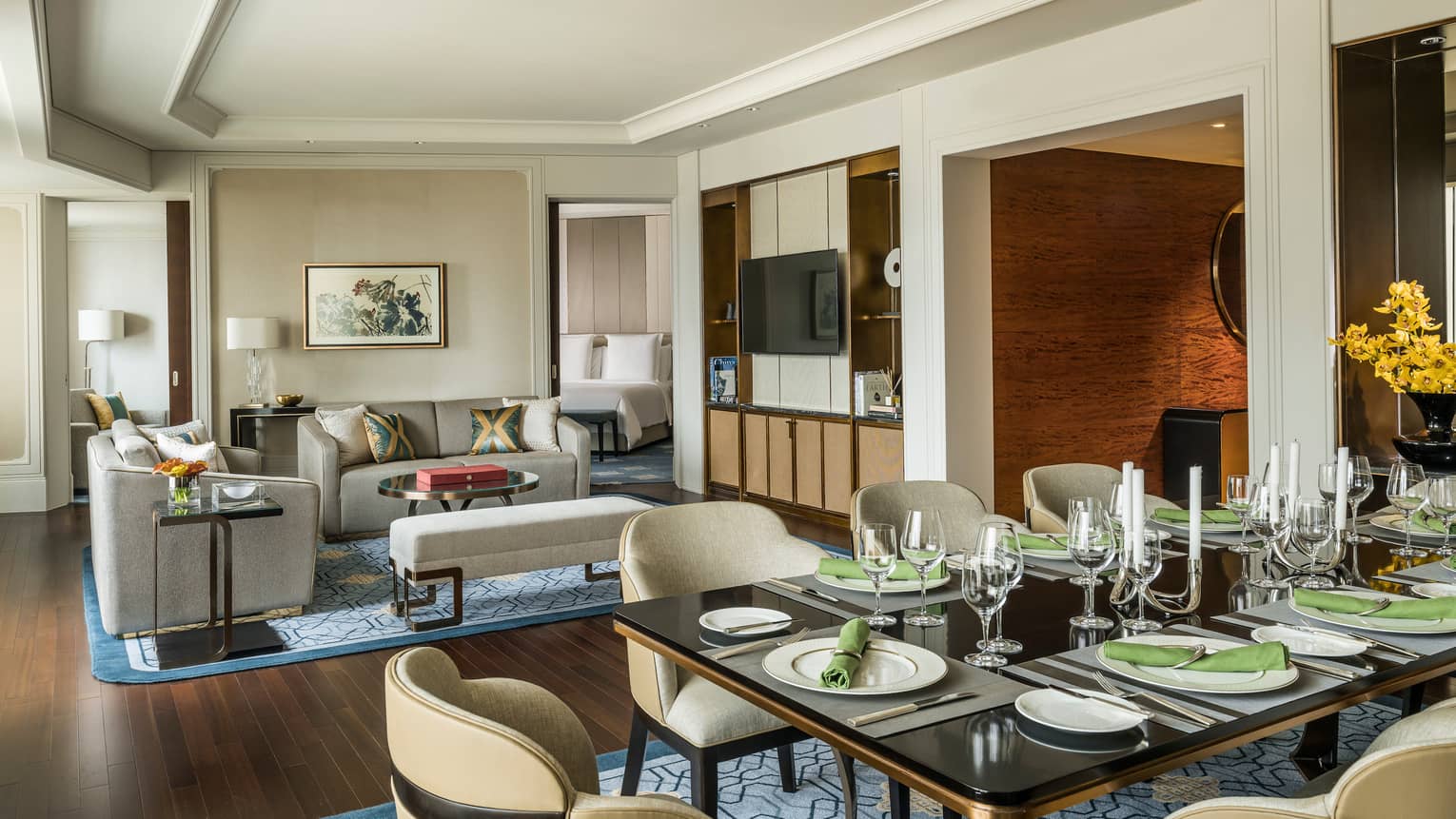 Royal Suite large dining table with formal place settings, green napkins by living room, TV console
