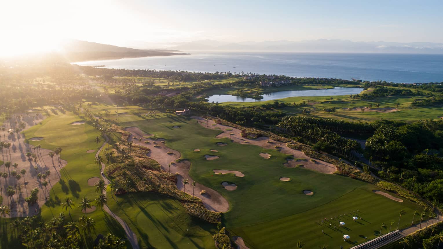 An overhead view of a golf course, sun shining brightly in the sky.