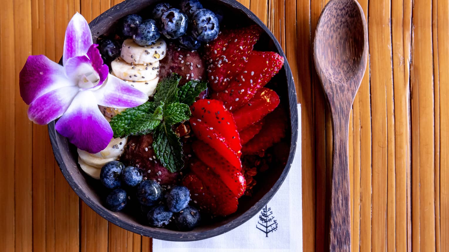 Acai bowl with strawberries, blueberries and a Hawaiian flower