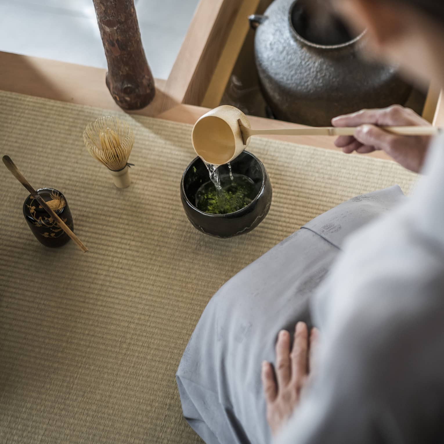 Woman kneels and pours tea from ladle during Tea Ceremony