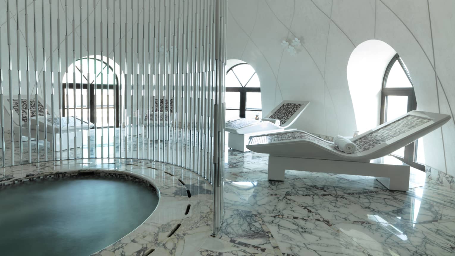 Round spa pool with metal rod divider, white lounge chairs on marble deck, white dome room