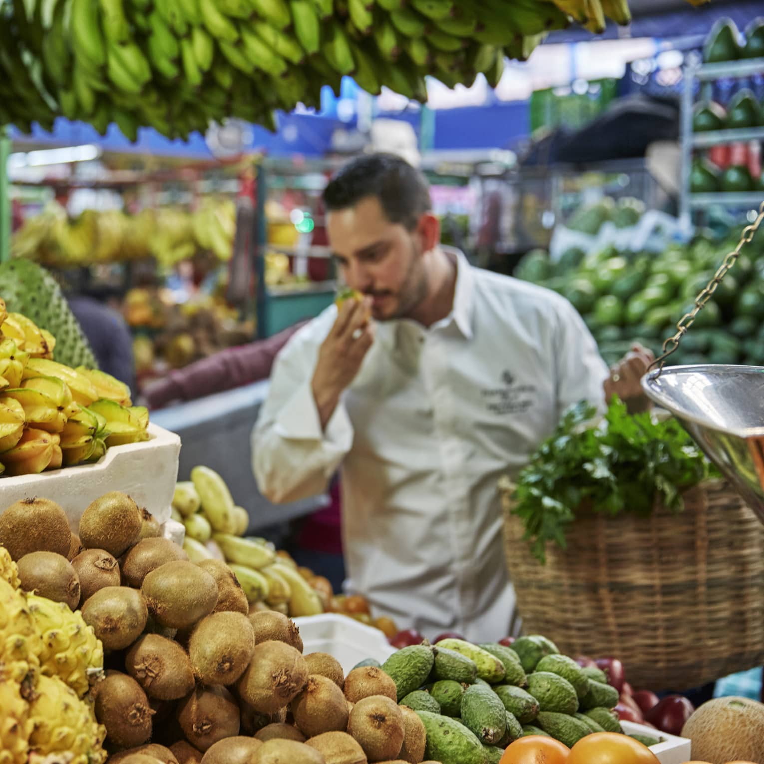 Chef smells tropical fruit at stand in market