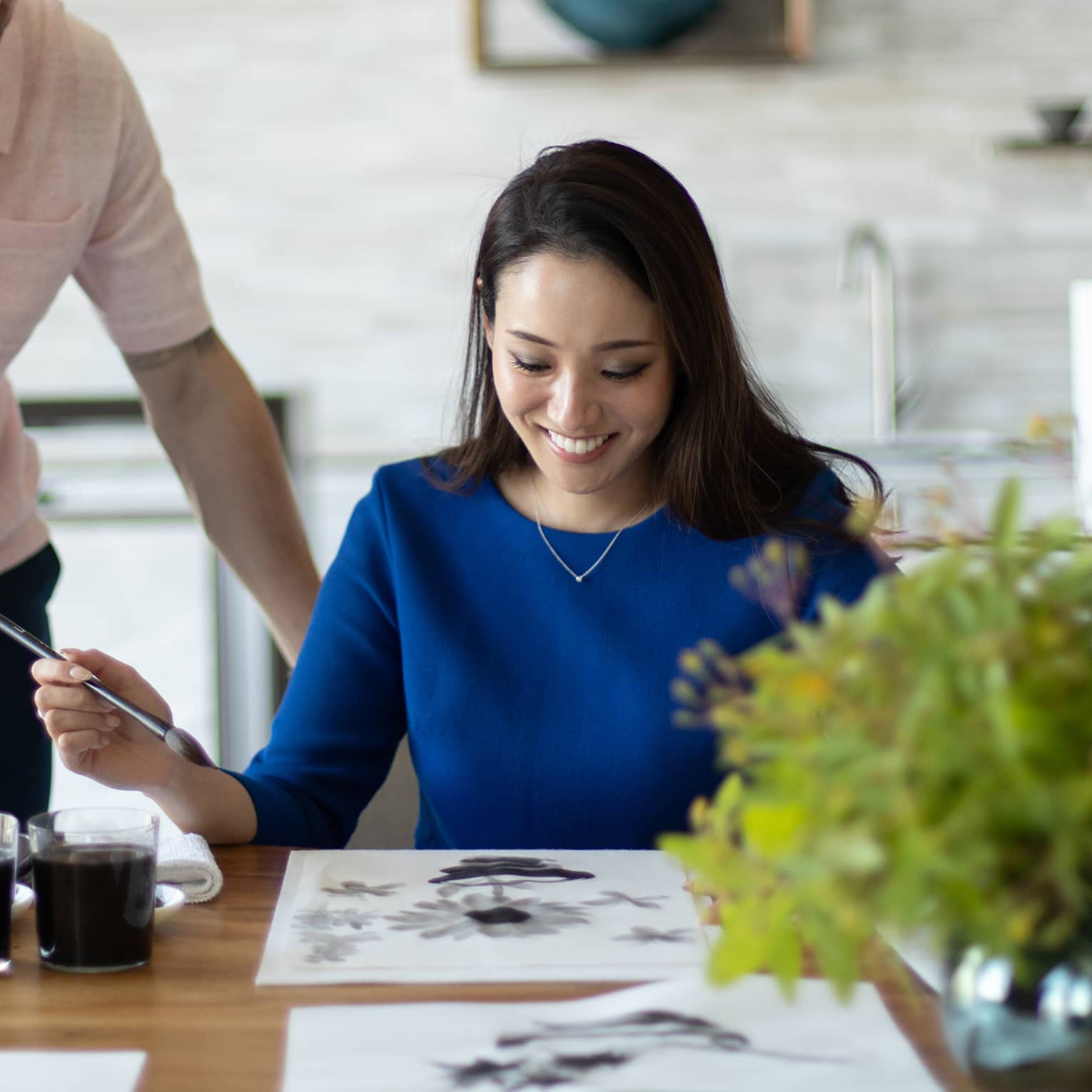 Person smiling while painting with watercolours at a table
