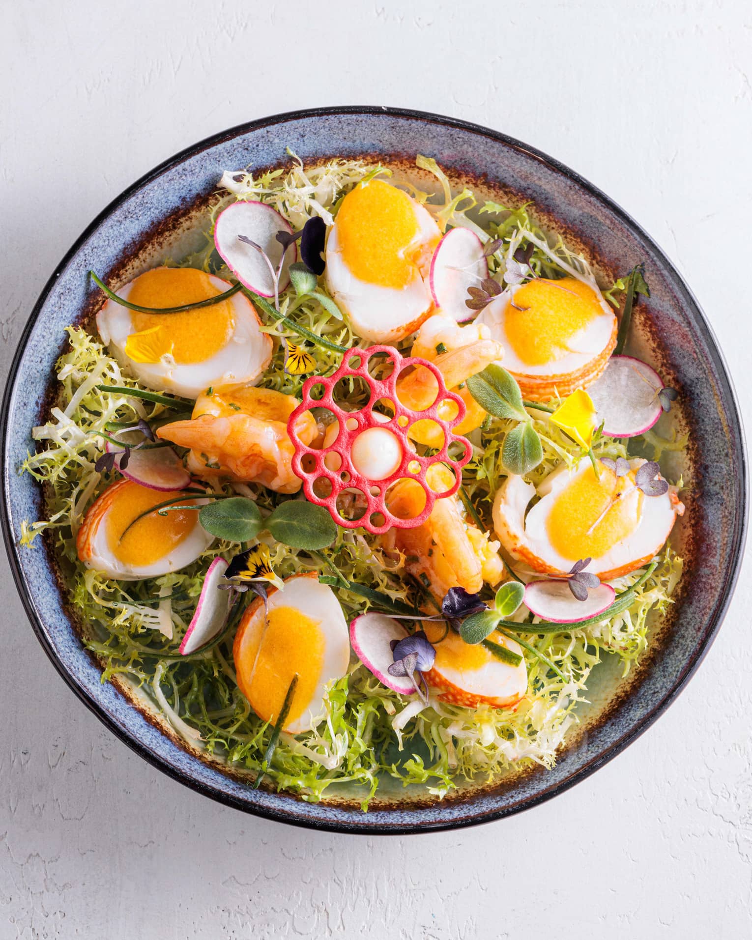 Bowl of greens, halved soft-boiled eggs, sliced radishes and a decorative garnish