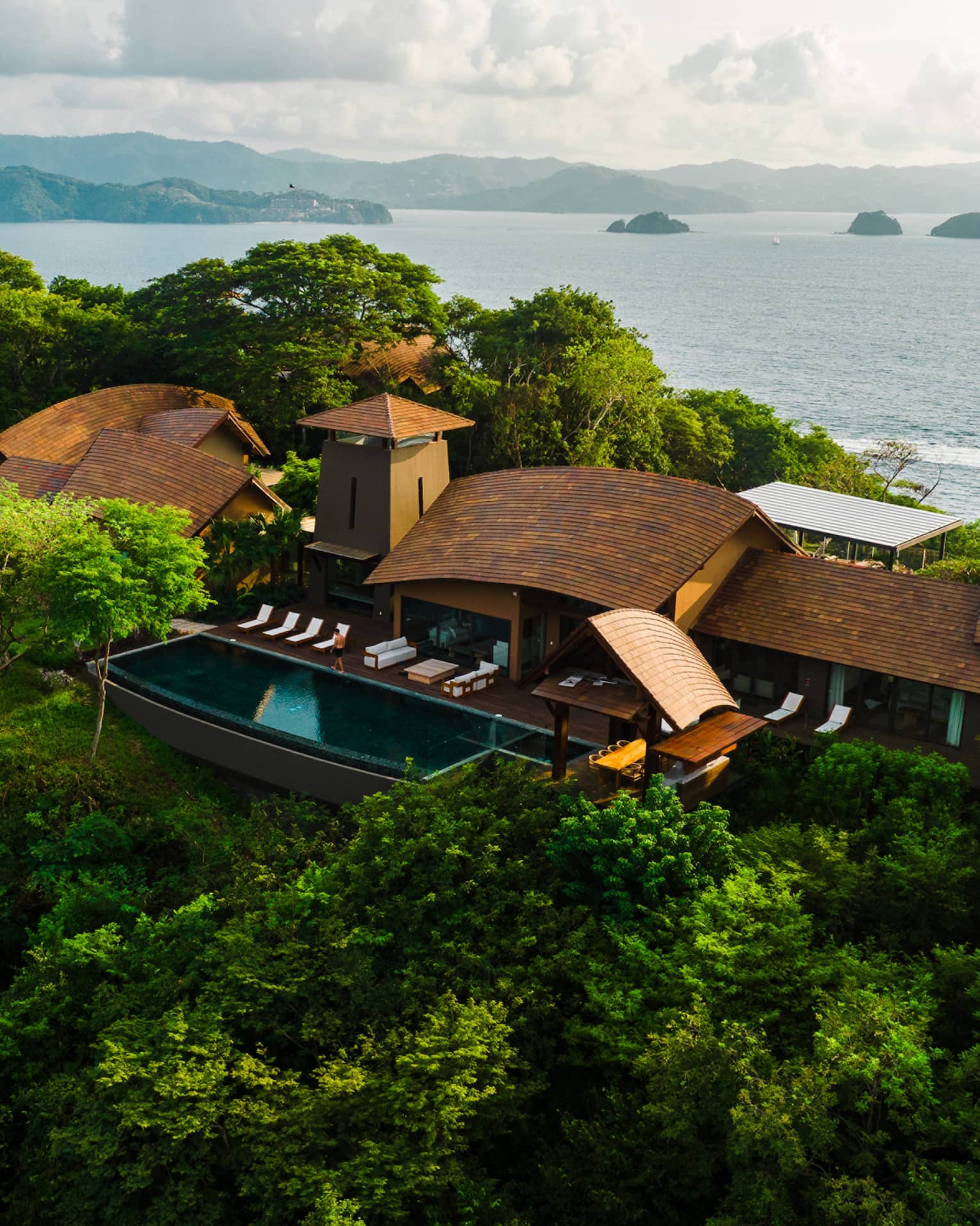 Villa tucked in a green hillside with the ocean in the background
