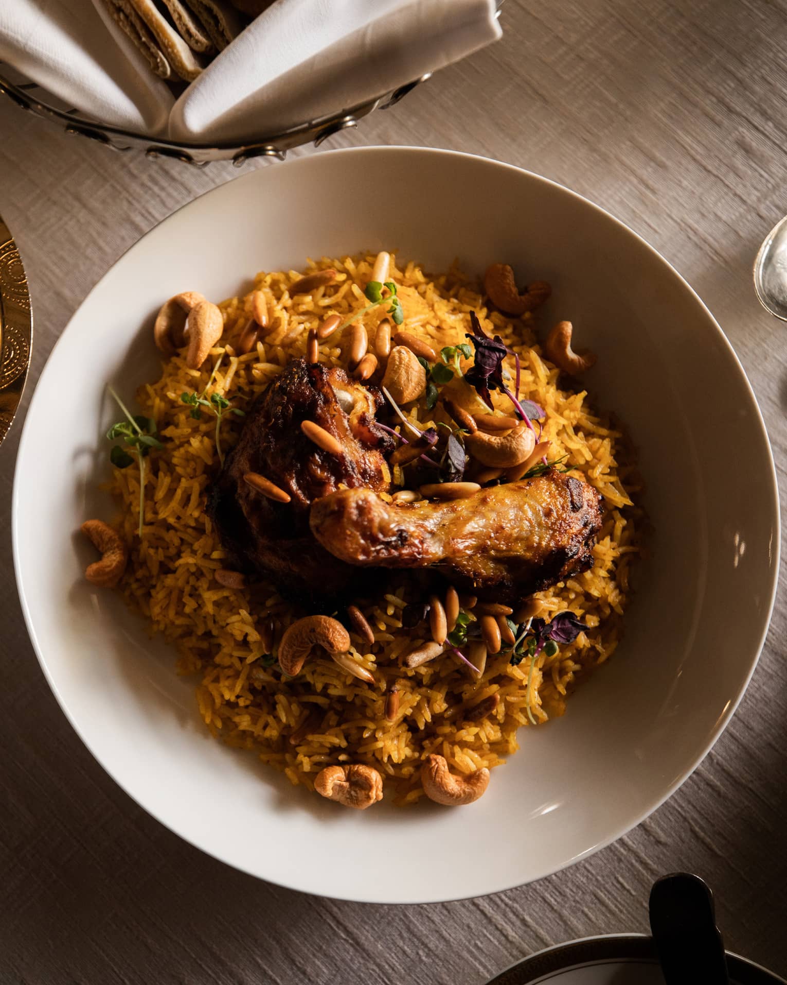 A view from above bowl of Kabsa, an Arabic chicken and rice dish, beautifully arranged with silver dishes surrounding it.