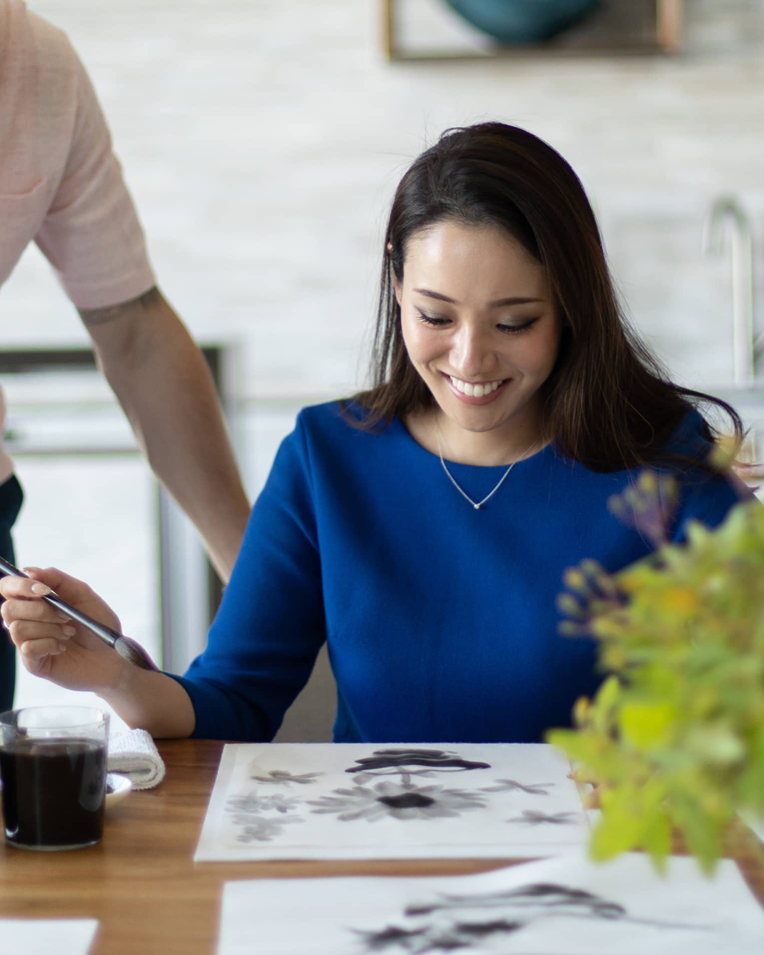 Person smiling while painting with watercolours at a table