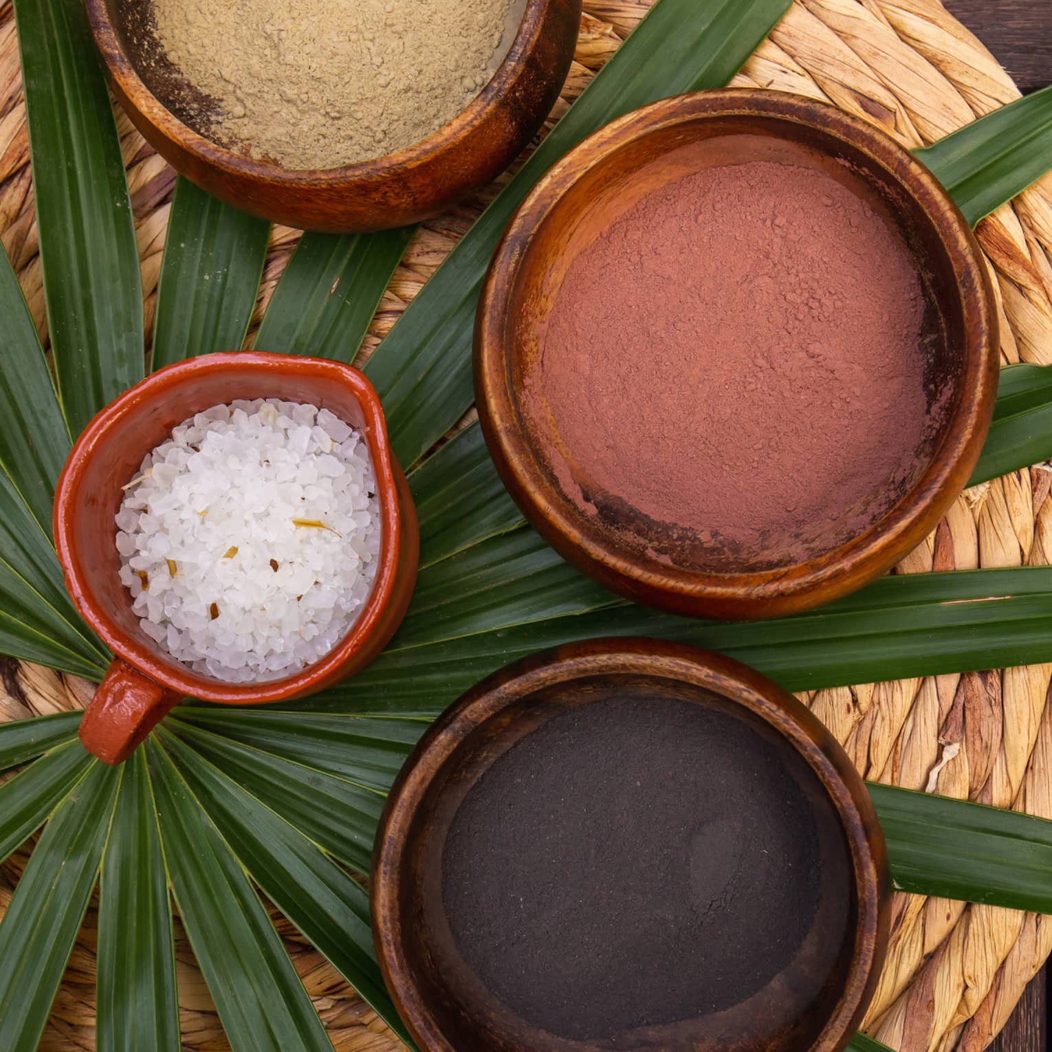 Various spa minerals in bowls on a large leaf.