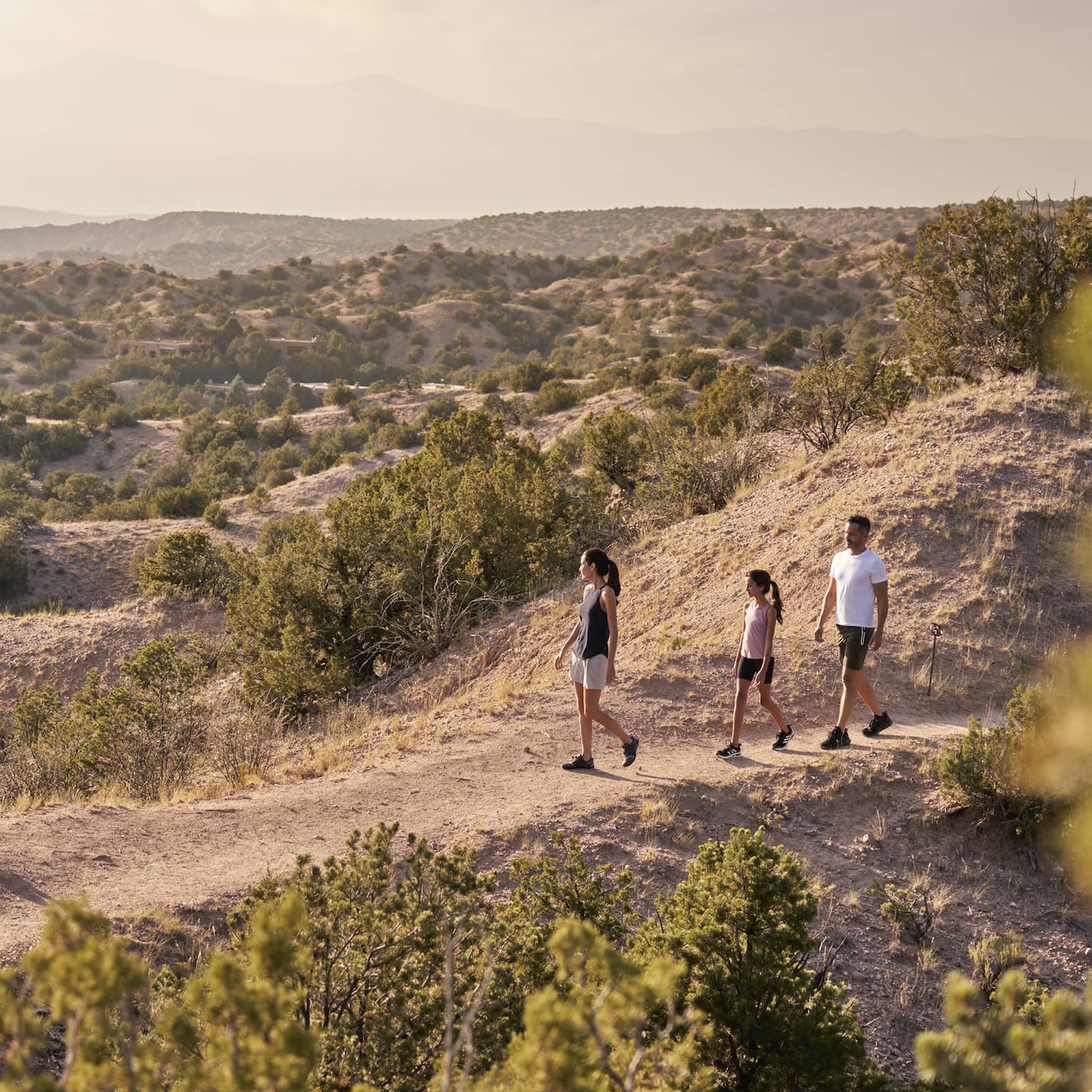A family of three hiking over sand.