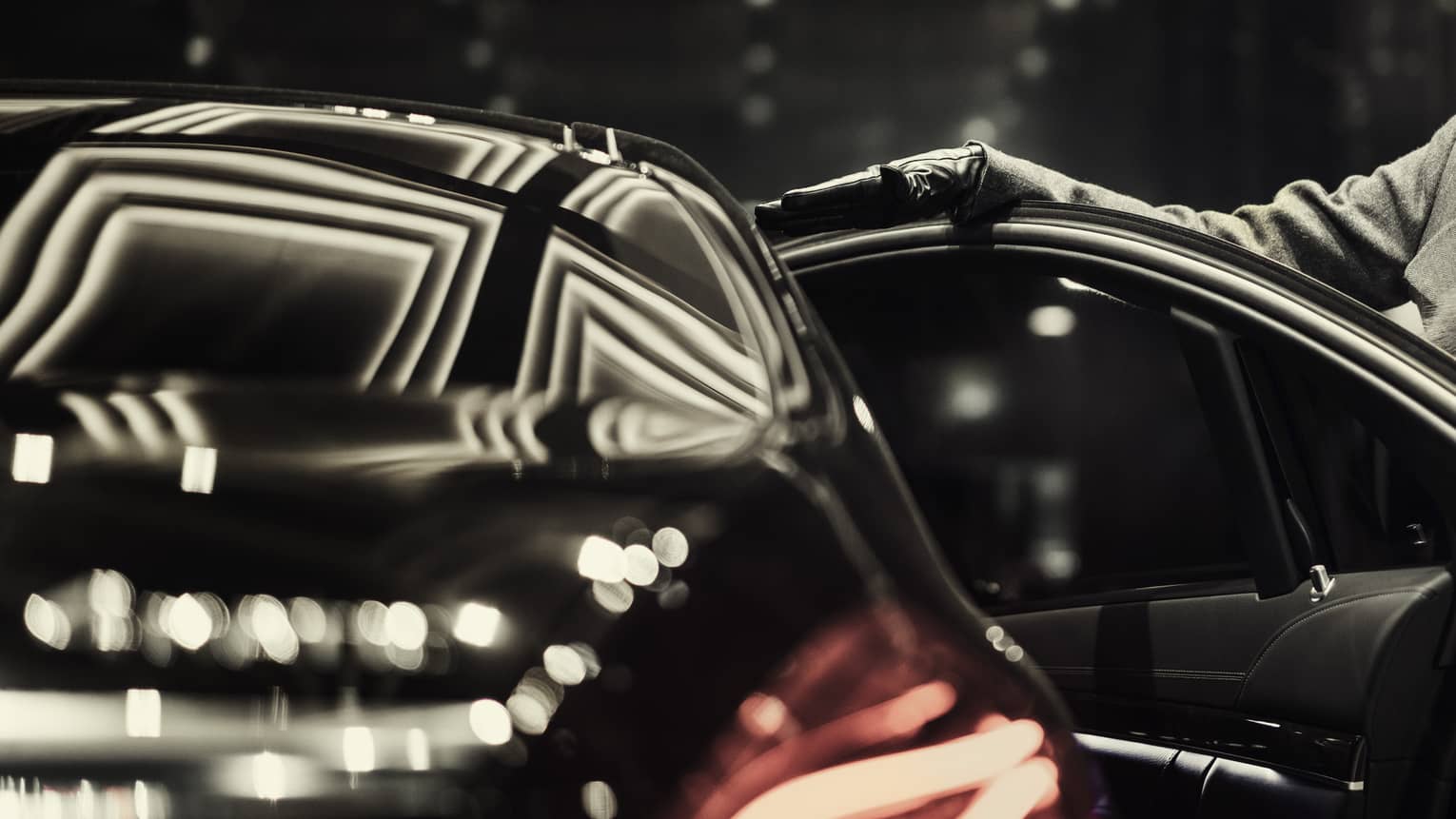 Woman wearing black fur hat, coat opens door of black luxury house car 