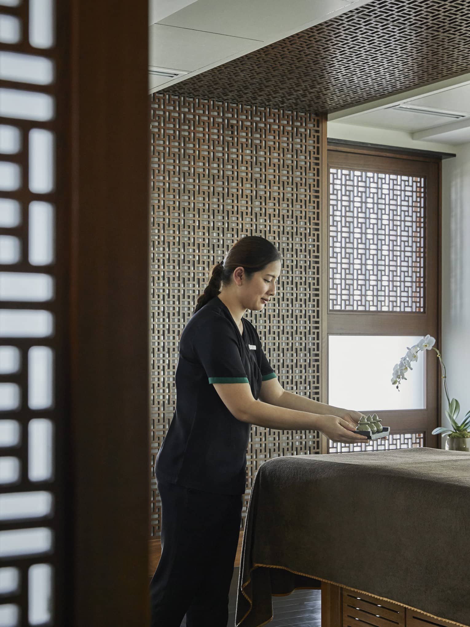 A female esthetician prepares a bed in the massage room.