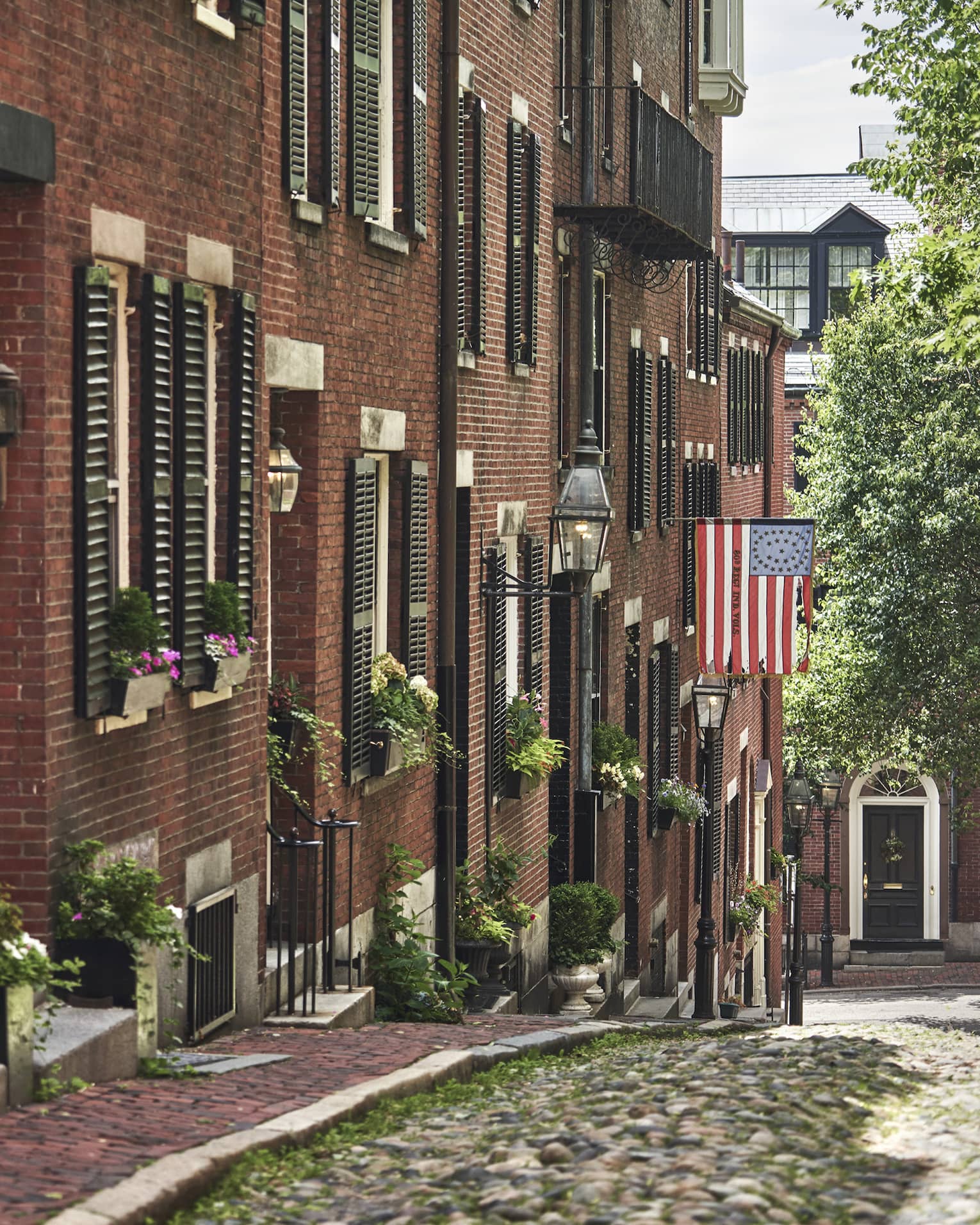 A cobblestone alley in Beacon Hill, lined with red brick residential buildings
