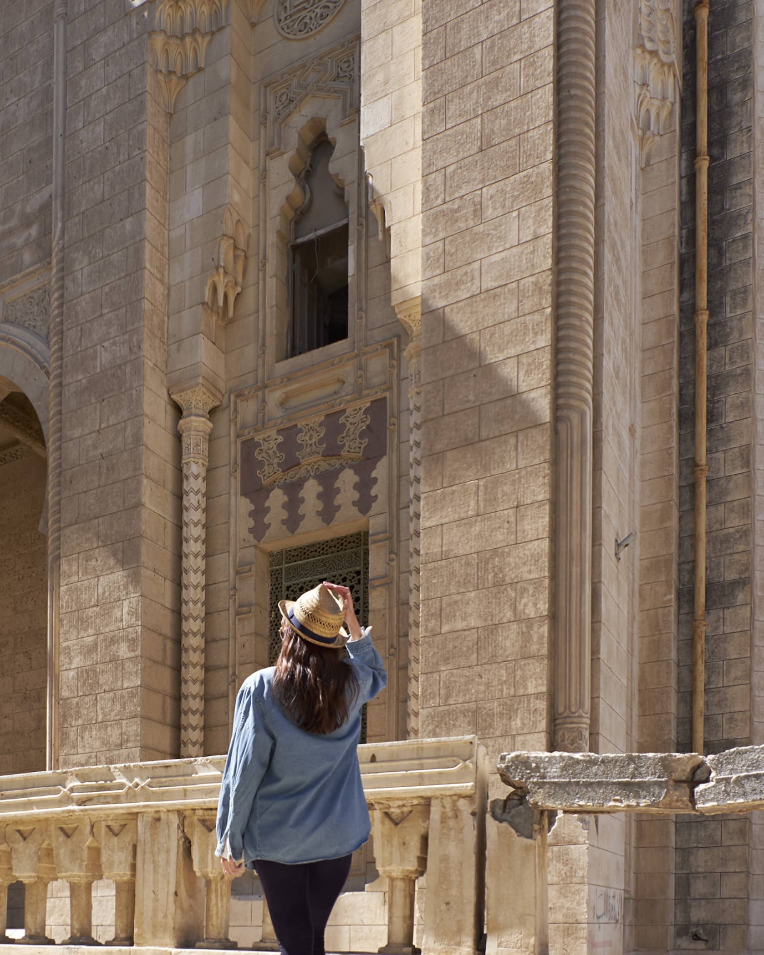 Woman looks up at historic palace exterior in Alexandria, Egypt
