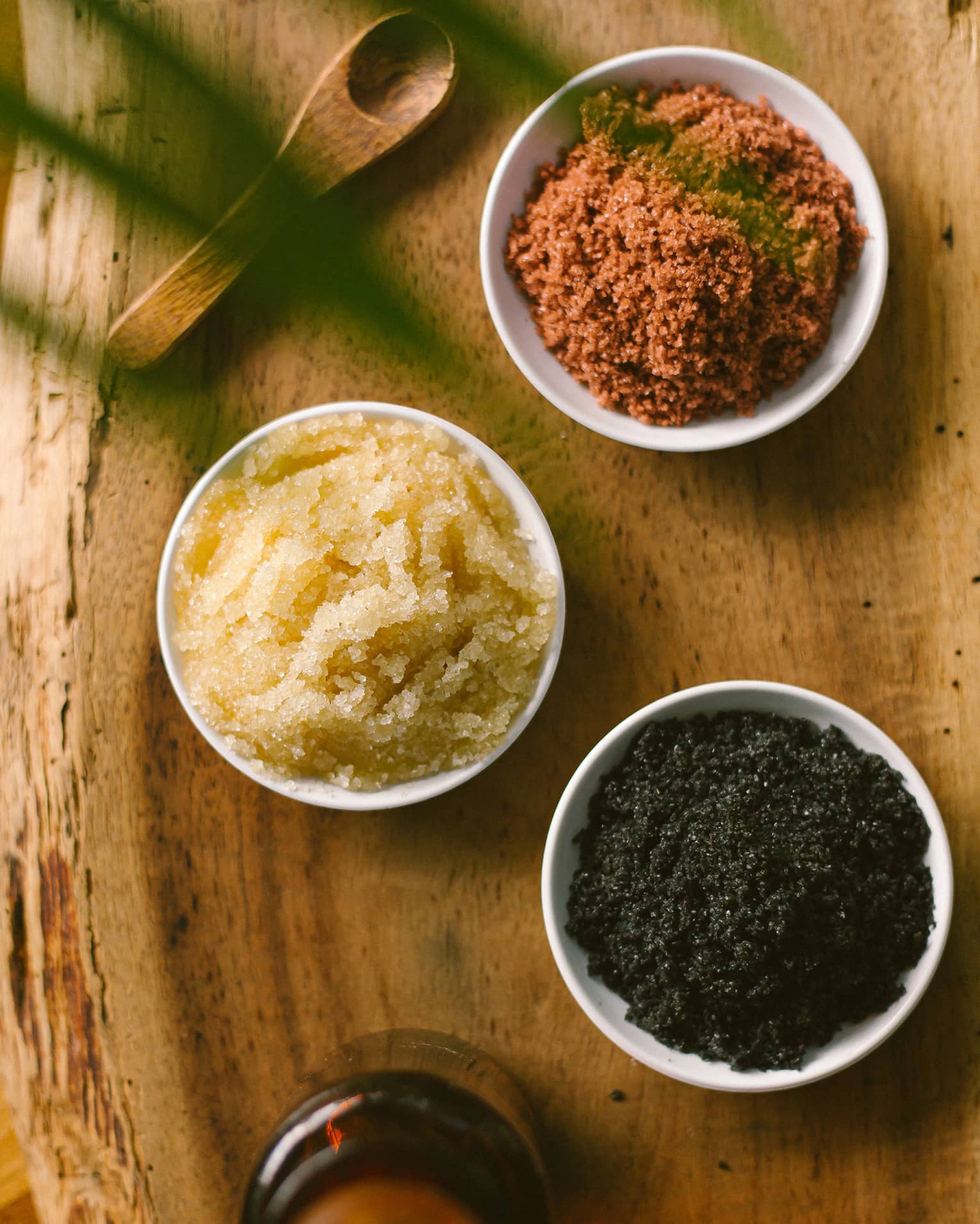 Aerial view of three dishes with salt scrubs on rustic wood platter