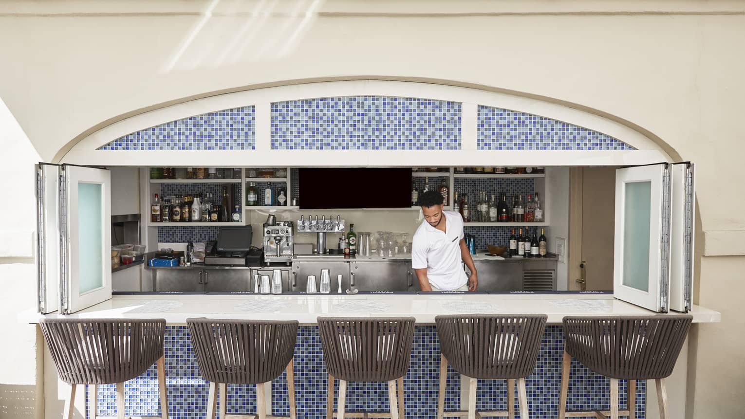 A team member standing behind a bar with stool.