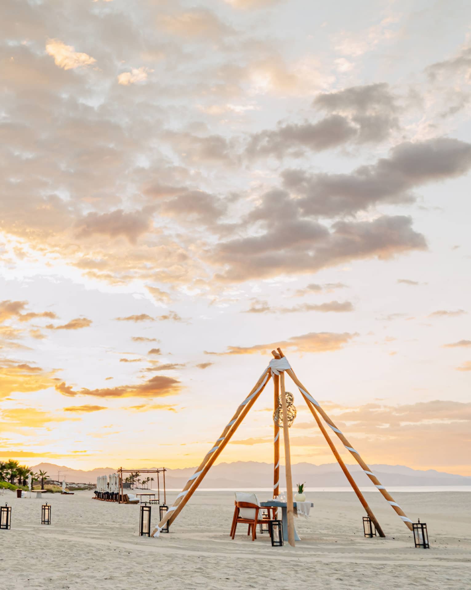 View of the sand on the beach with a sunset in the background and palm trees.