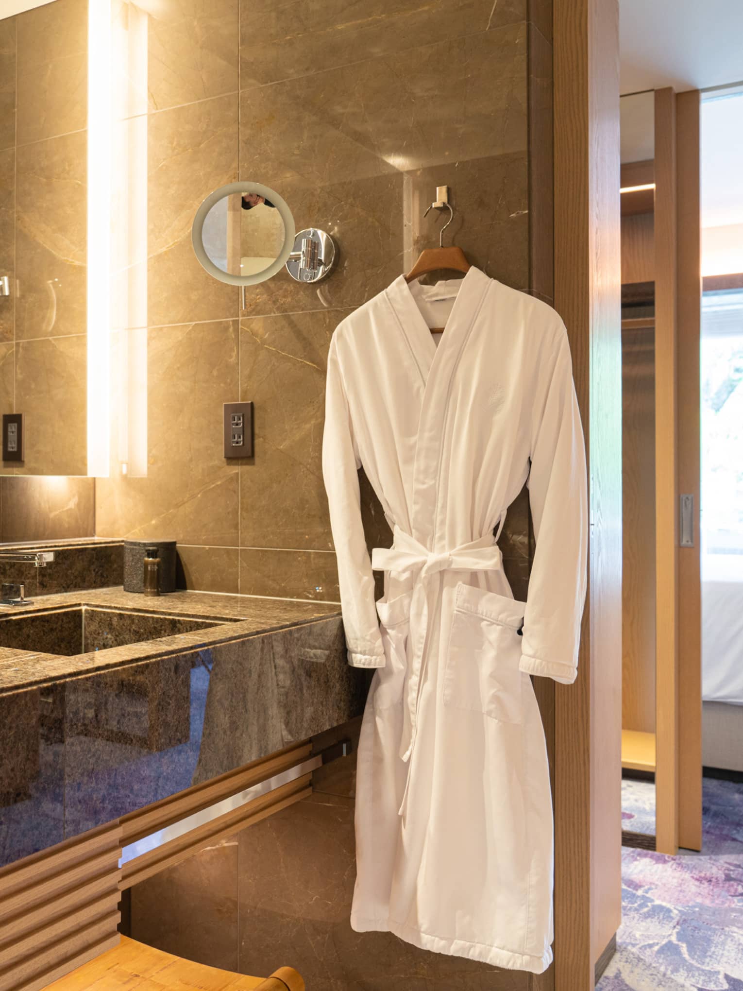 Luxury bathroom with a double-sink vanity, large mirror and a plush white robe hanging beside the counter