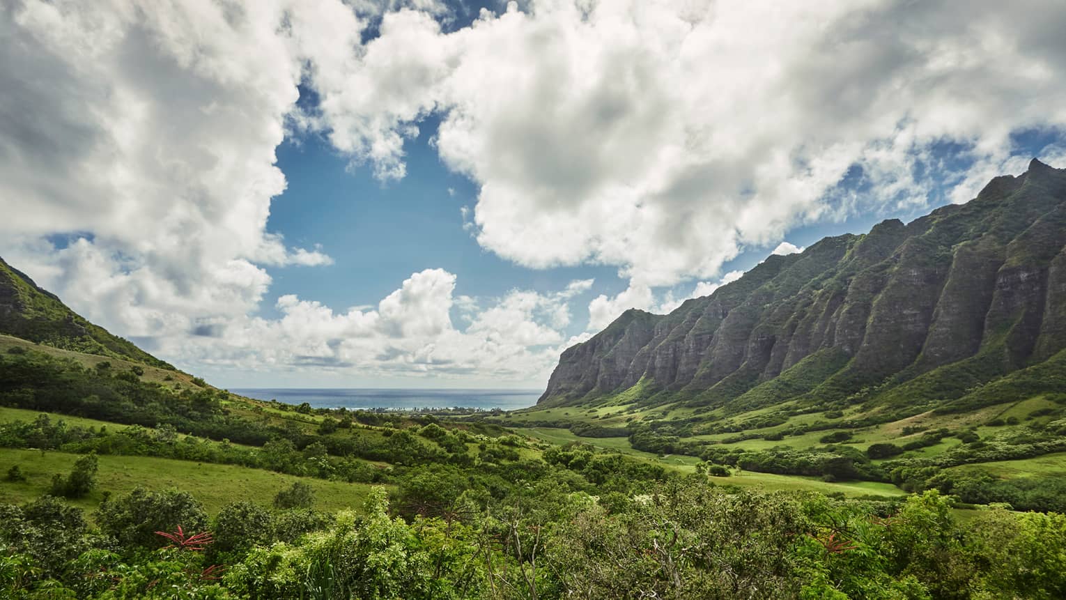 Oahu sweeping green cliffs, mountains, under blue skies
