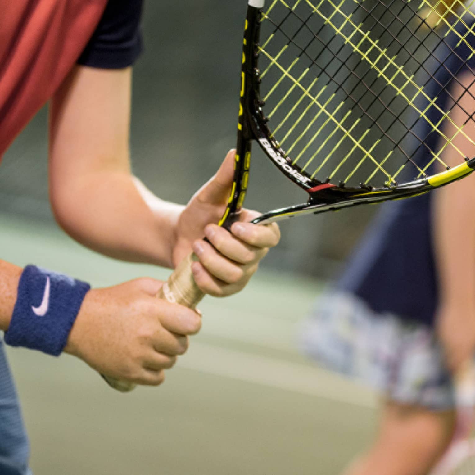 Close-up of hands holding yellow-and-black tennis racket