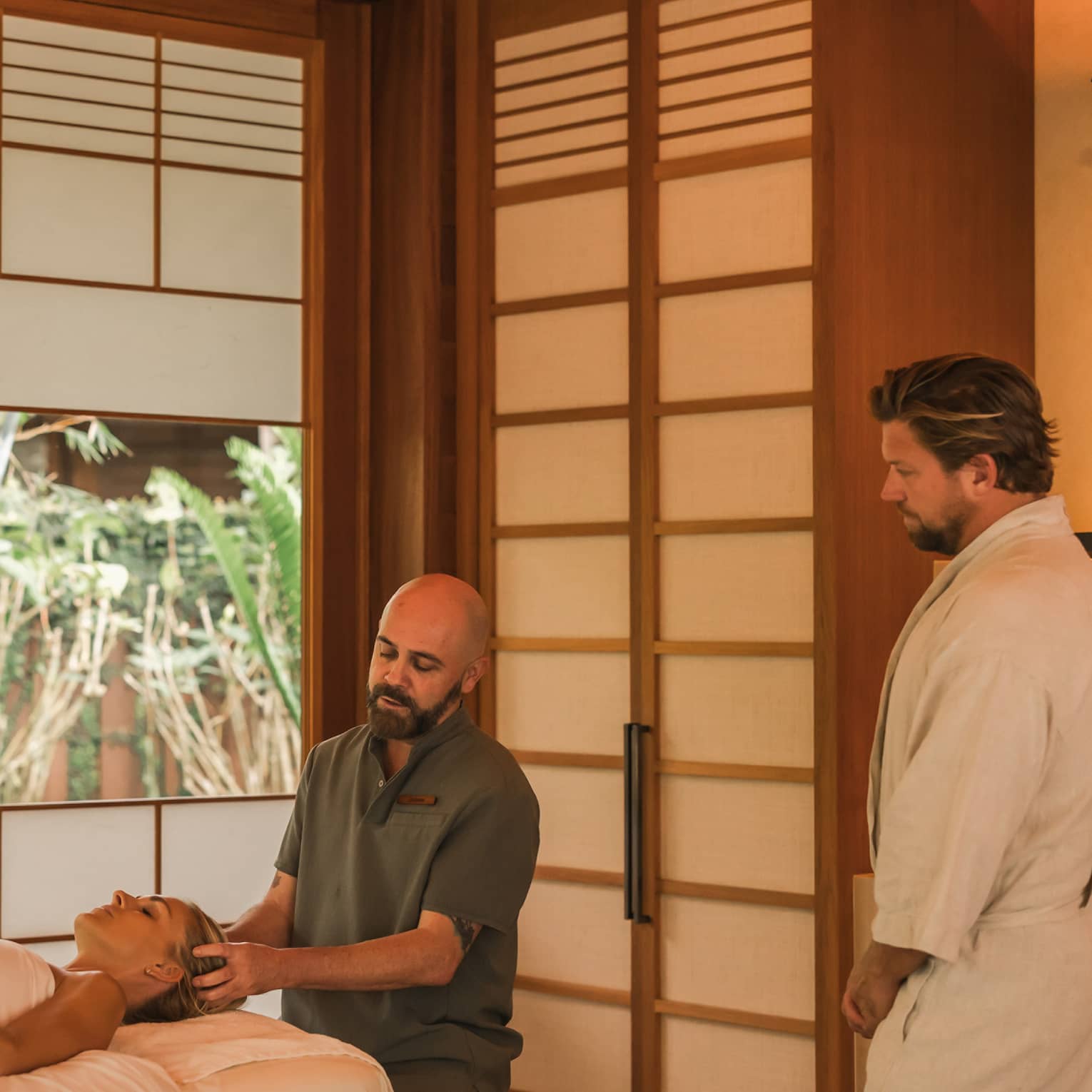 Man performs head massage on a woman laying on spa treatment table