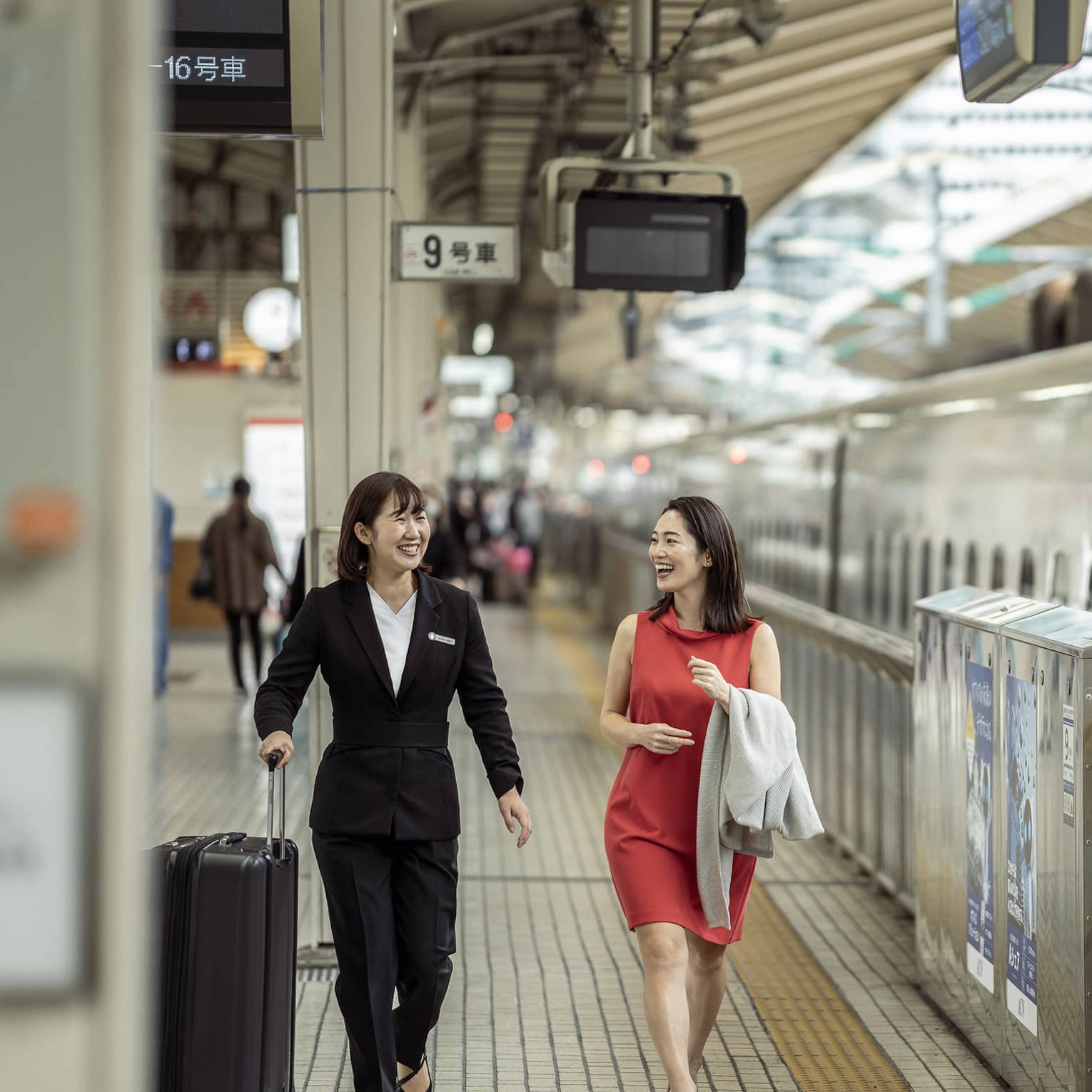 Train station greeter walks with female guest along the train platform
