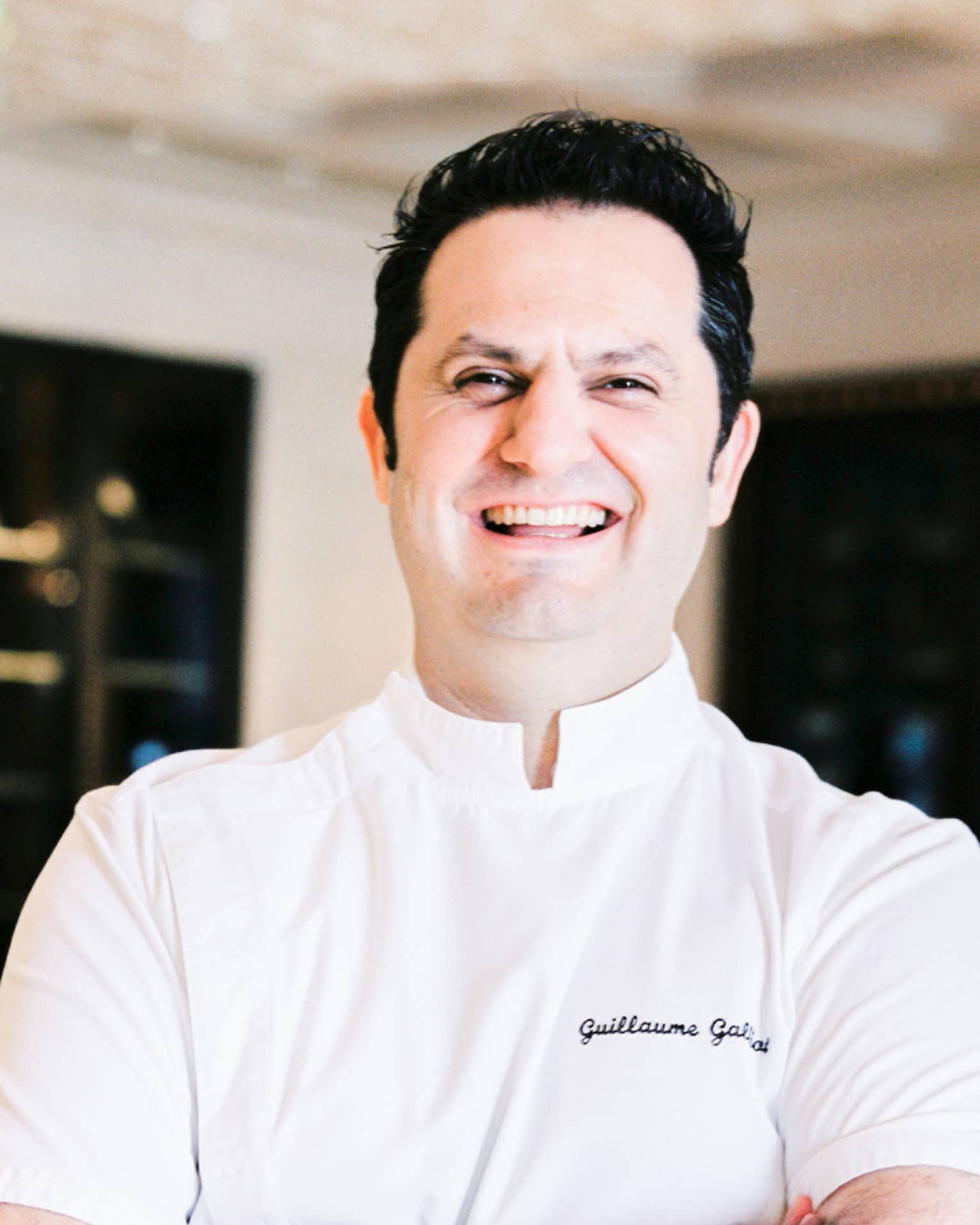 Portrait photo of Chef Guillaume Galliot in uniform and crossing arms