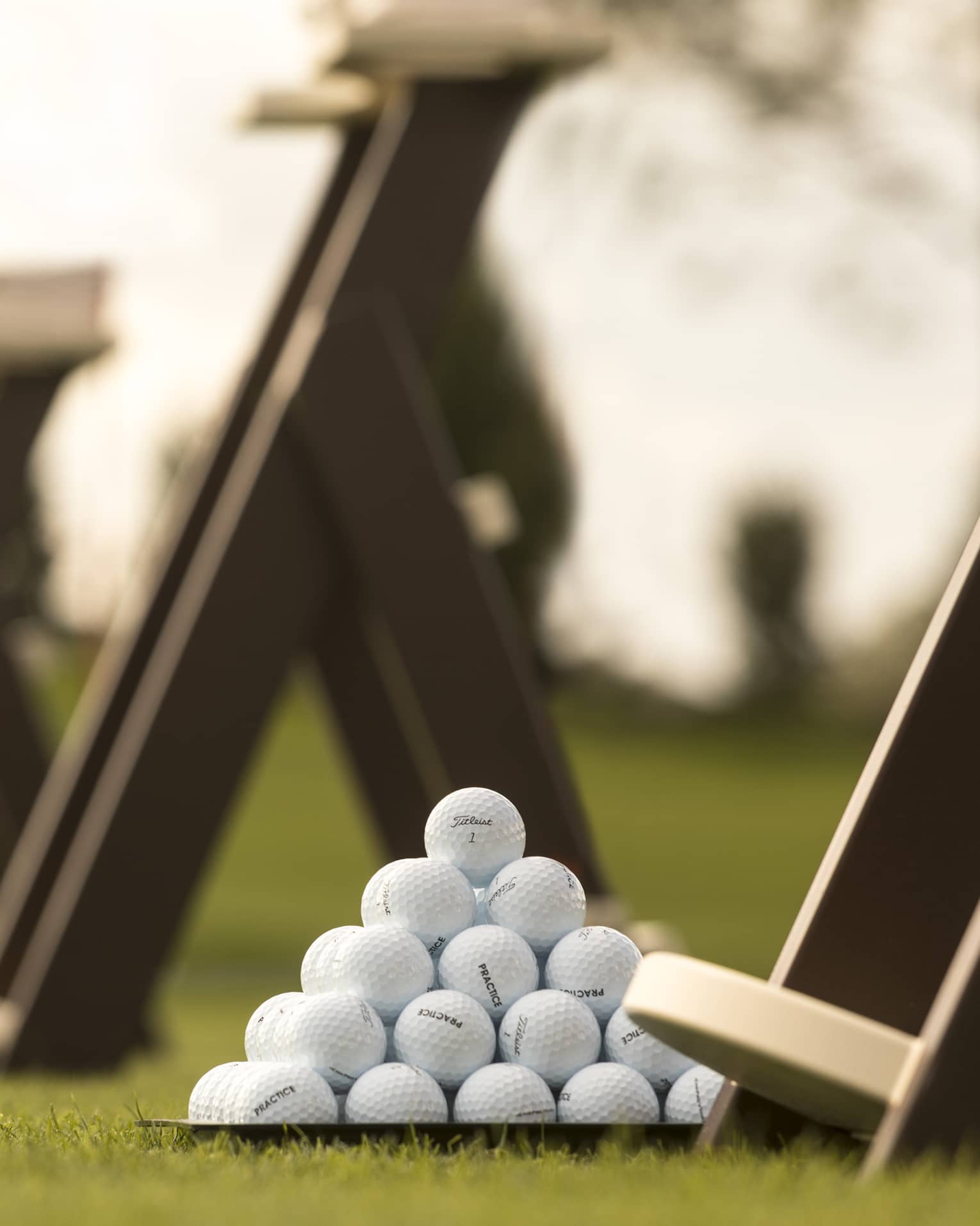 Stacks of white golf balls on lawn in front of wood panels