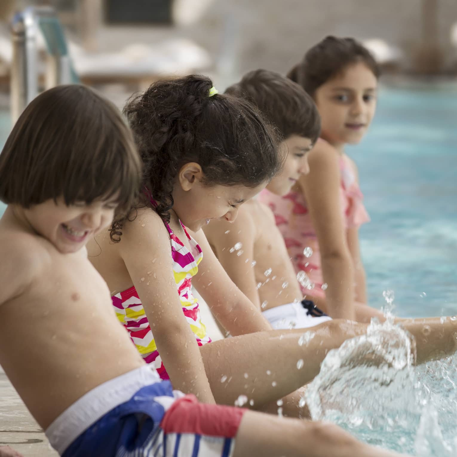 Several children splashing at the pool.