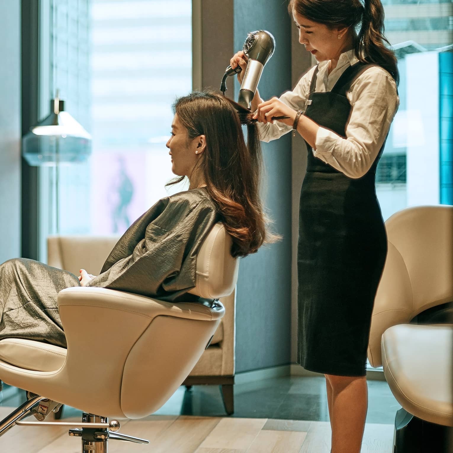 Hair stylist blow dries woman's hair in hotel salon