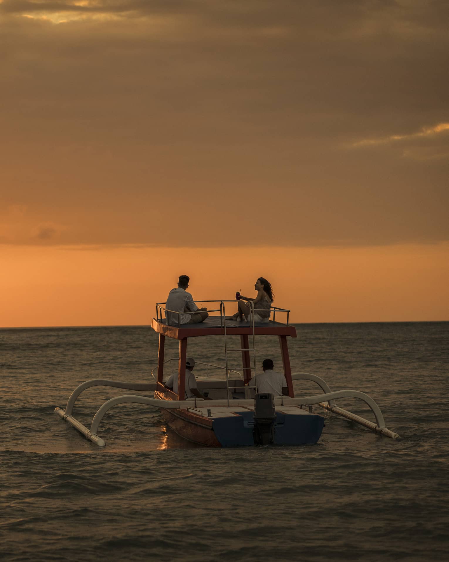 Sunset cruise boat on water under orange sky