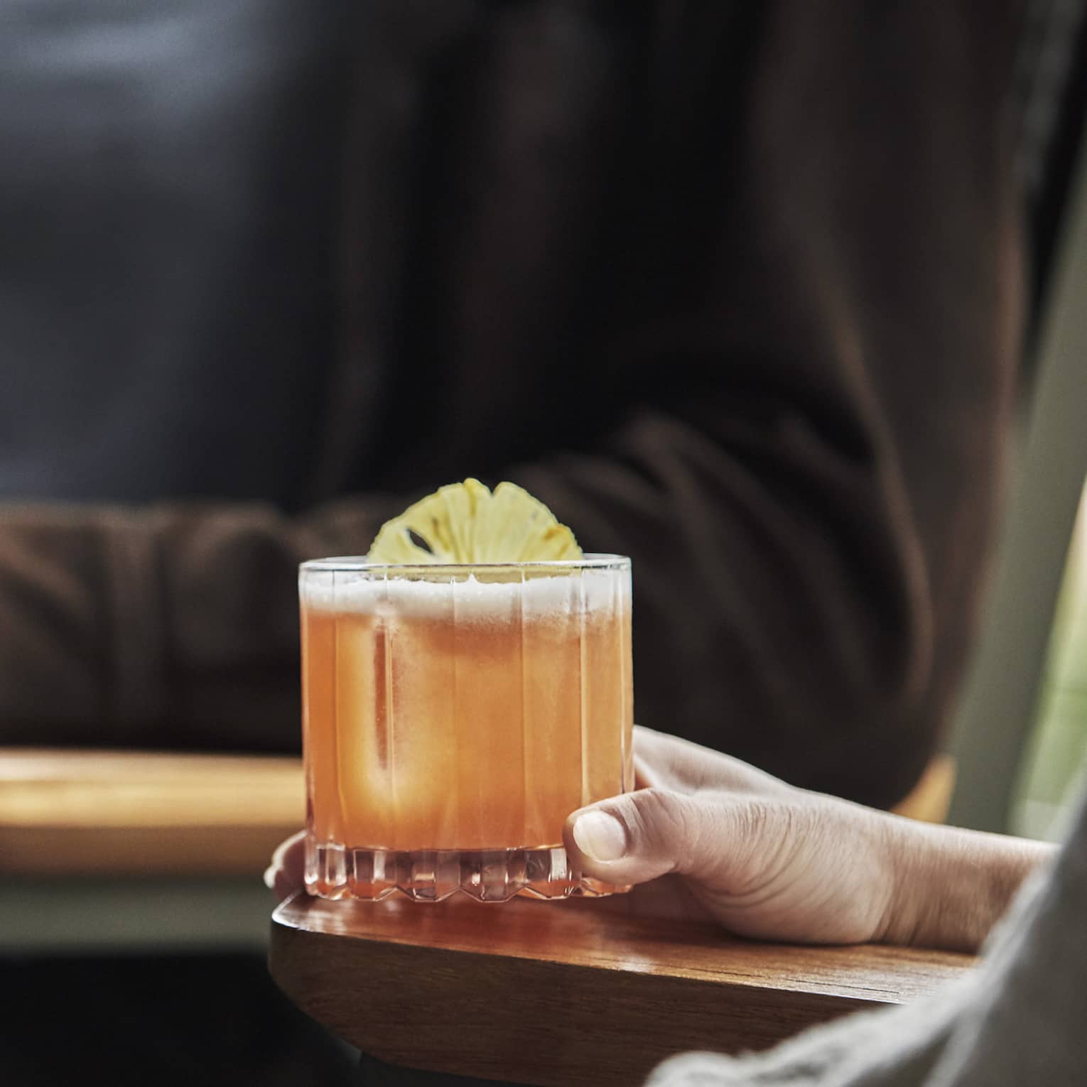 Close-up of two people sitting, holding cocktail and glass of wine