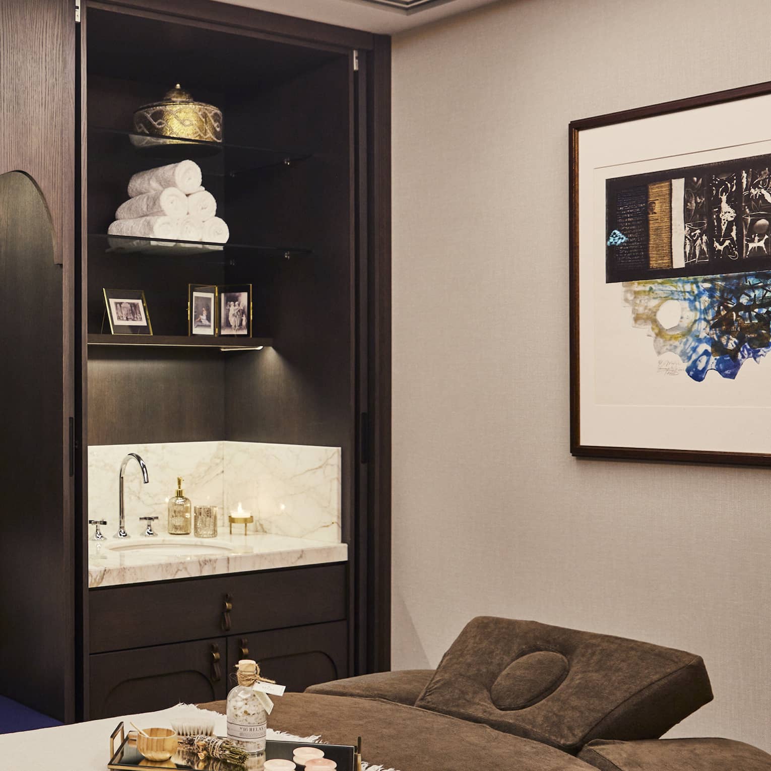 Kuma Spa treatment bed with tray with oils next to large wood cabinet with pillows and sink