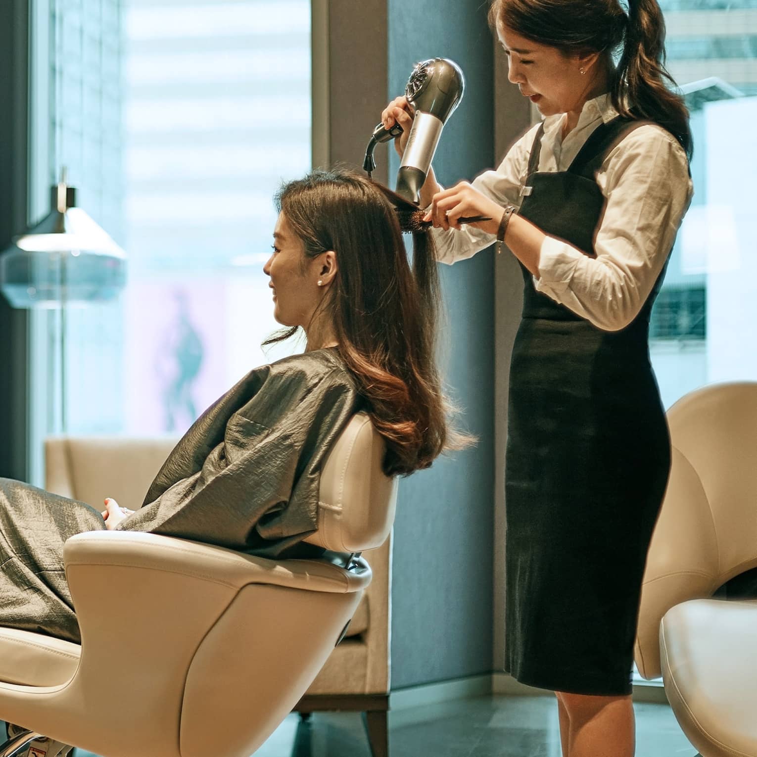 Hair stylist blow dries woman's hair in hotel salon