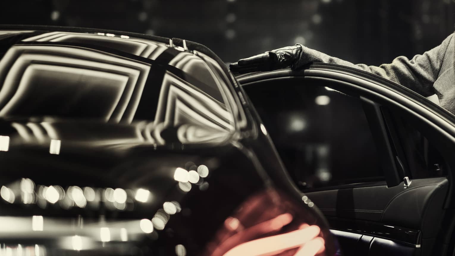 Woman wearing black fur hat, coat opens door of black luxury house car 
