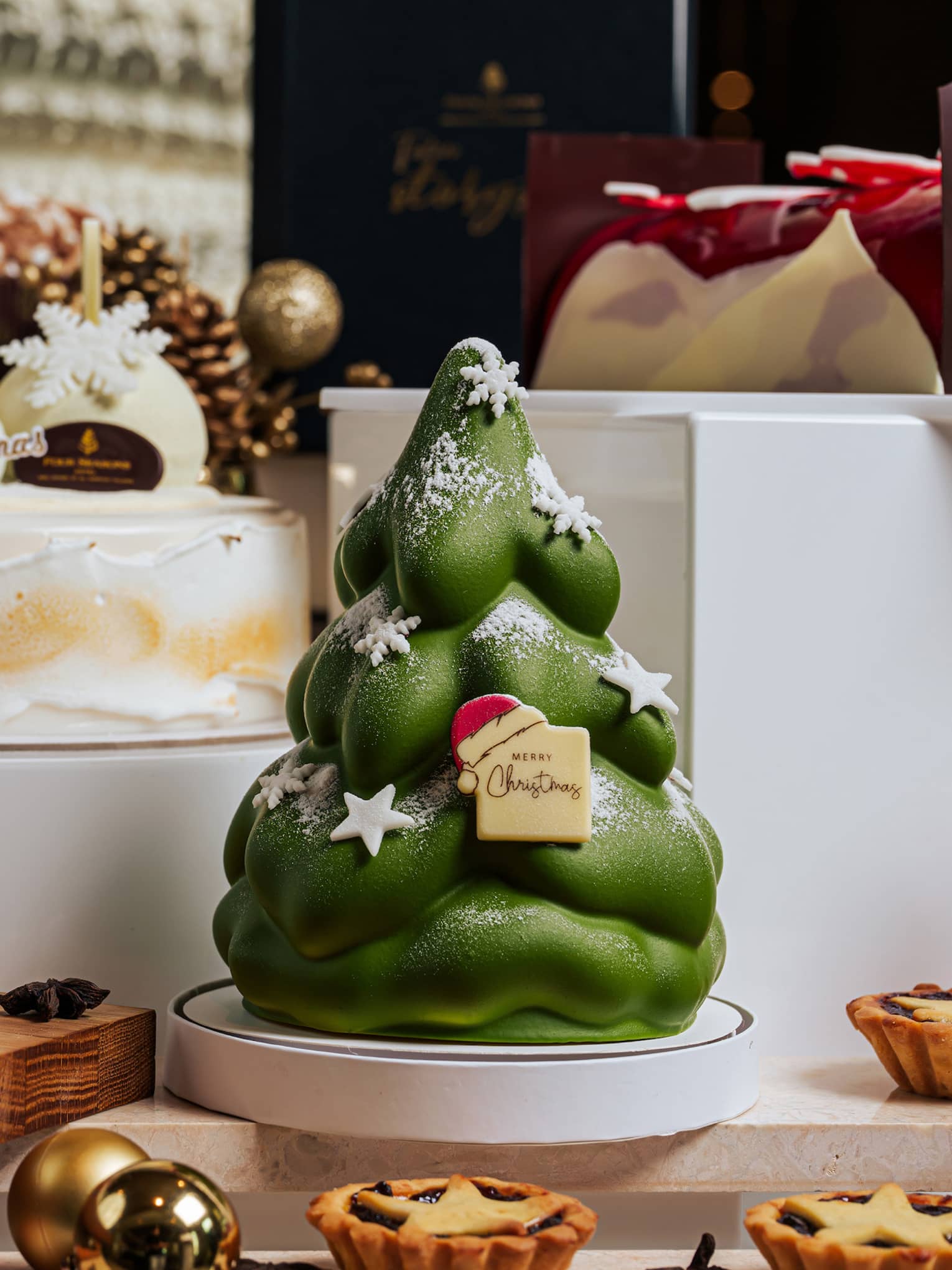 Table with tiered white boxes set up with holiday desserts and decor