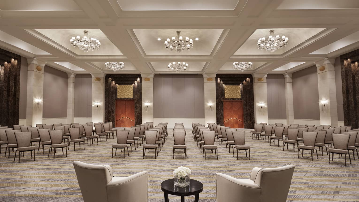 A function room with a series of grey chairs, and illuminated by twelve crystal chandeliers. 