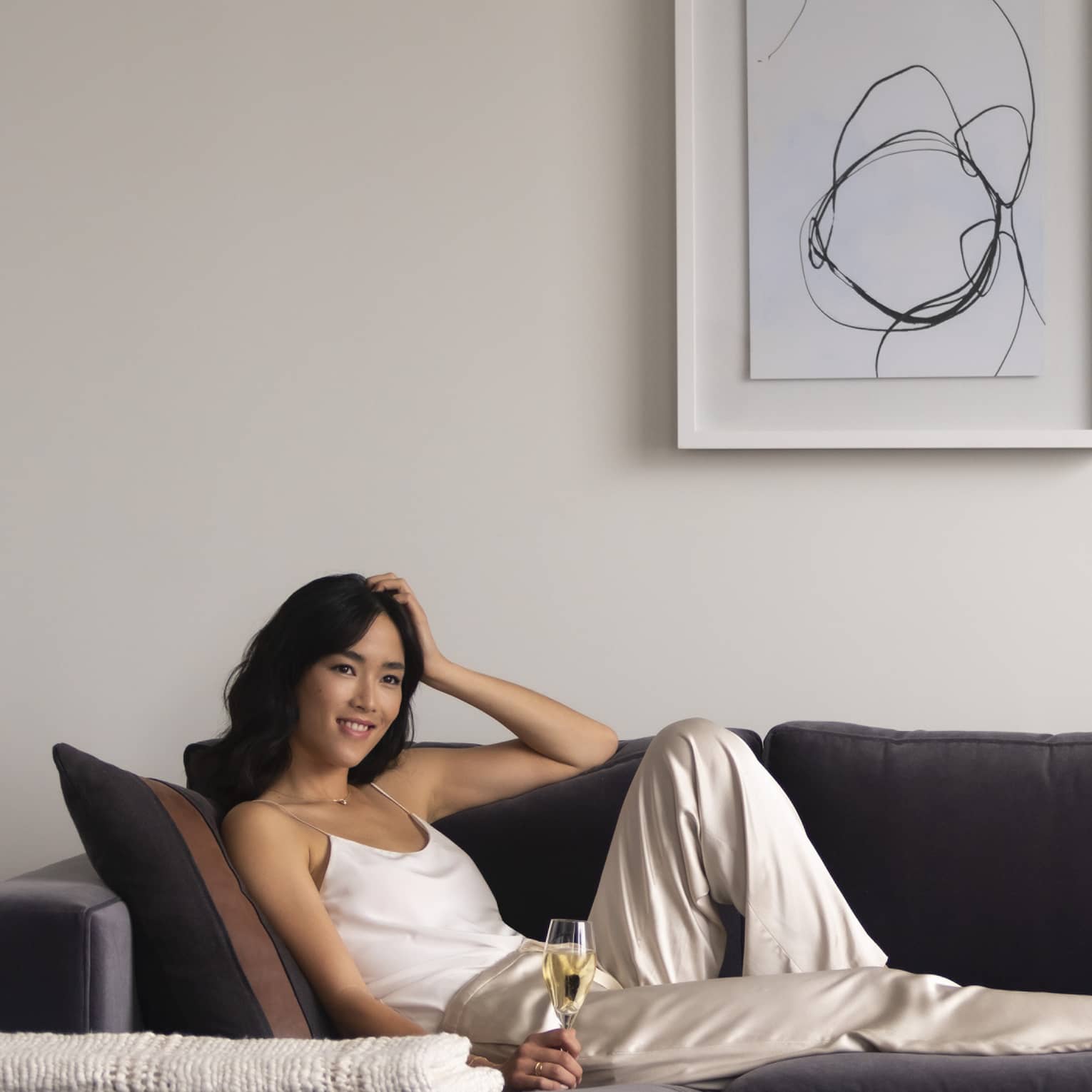 Woman lays on a sofa with glass of champagne