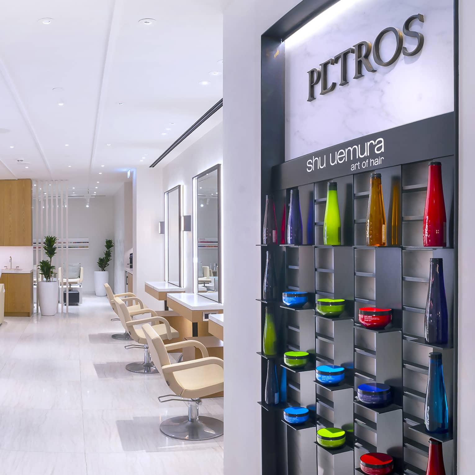 Petros Hair Salon reception desk with hair products on wall and view into salon