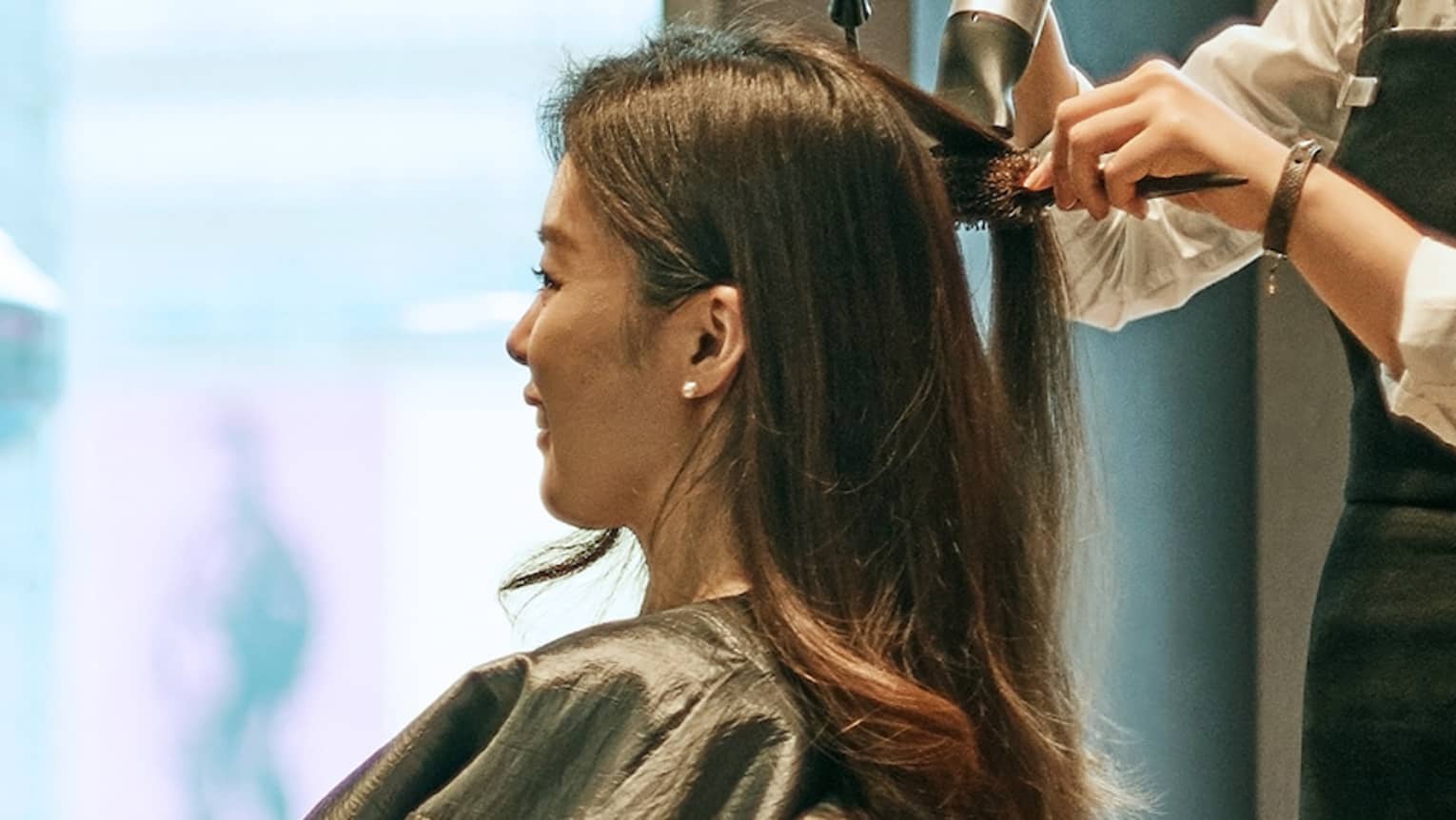 Hair stylist blow dries woman's hair in hotel salon
