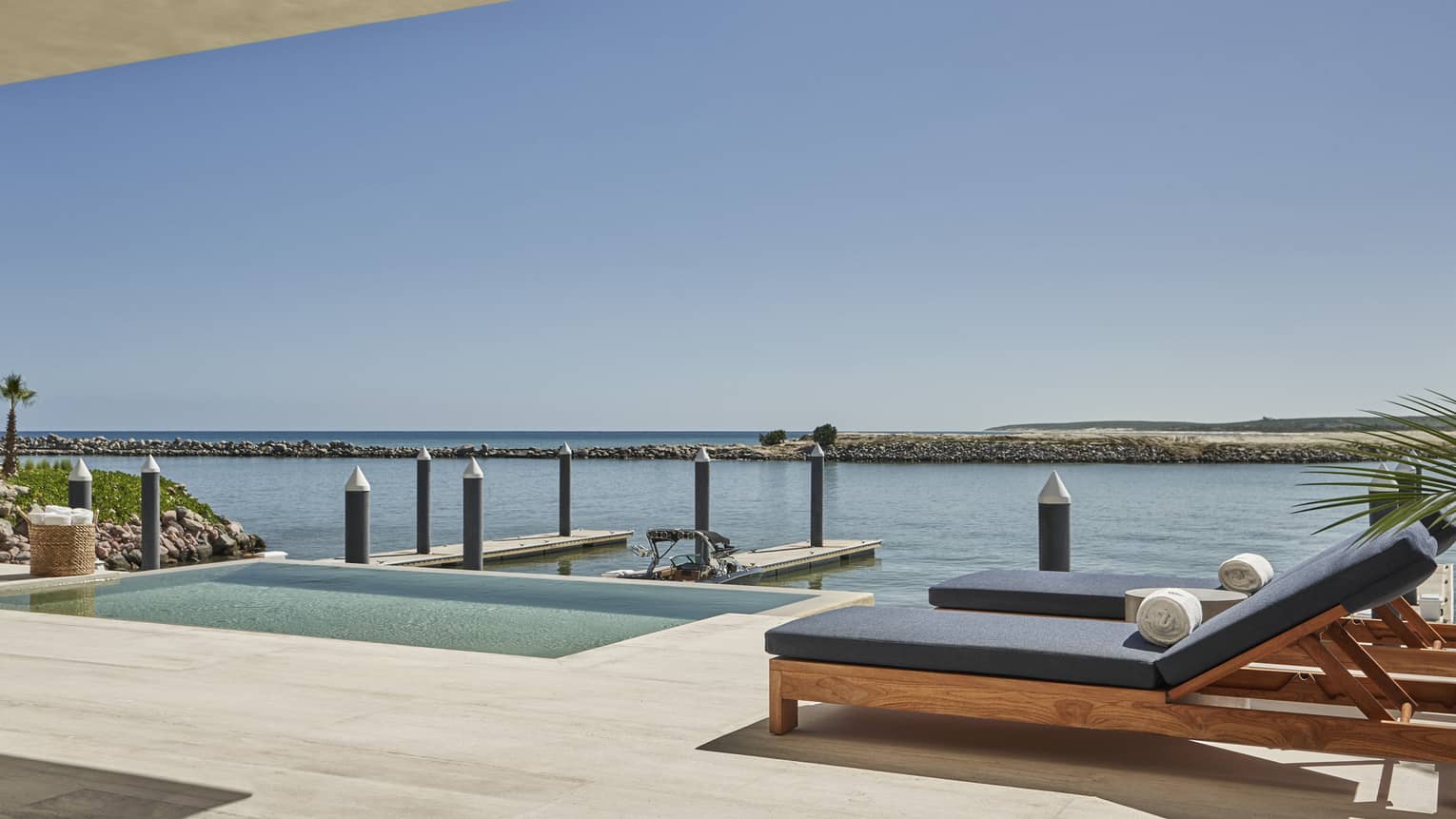 Modern terrace with teak lounge chairs and water view with boat slip