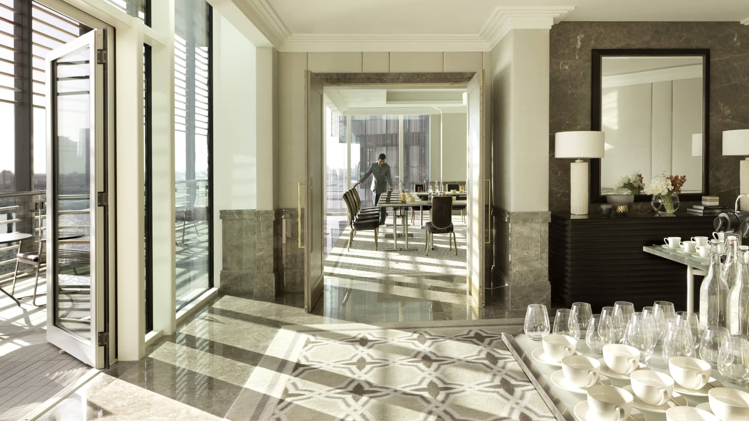 Sun streams into the bright Al Fahidi event room as staff sets meeting table behind coffee service